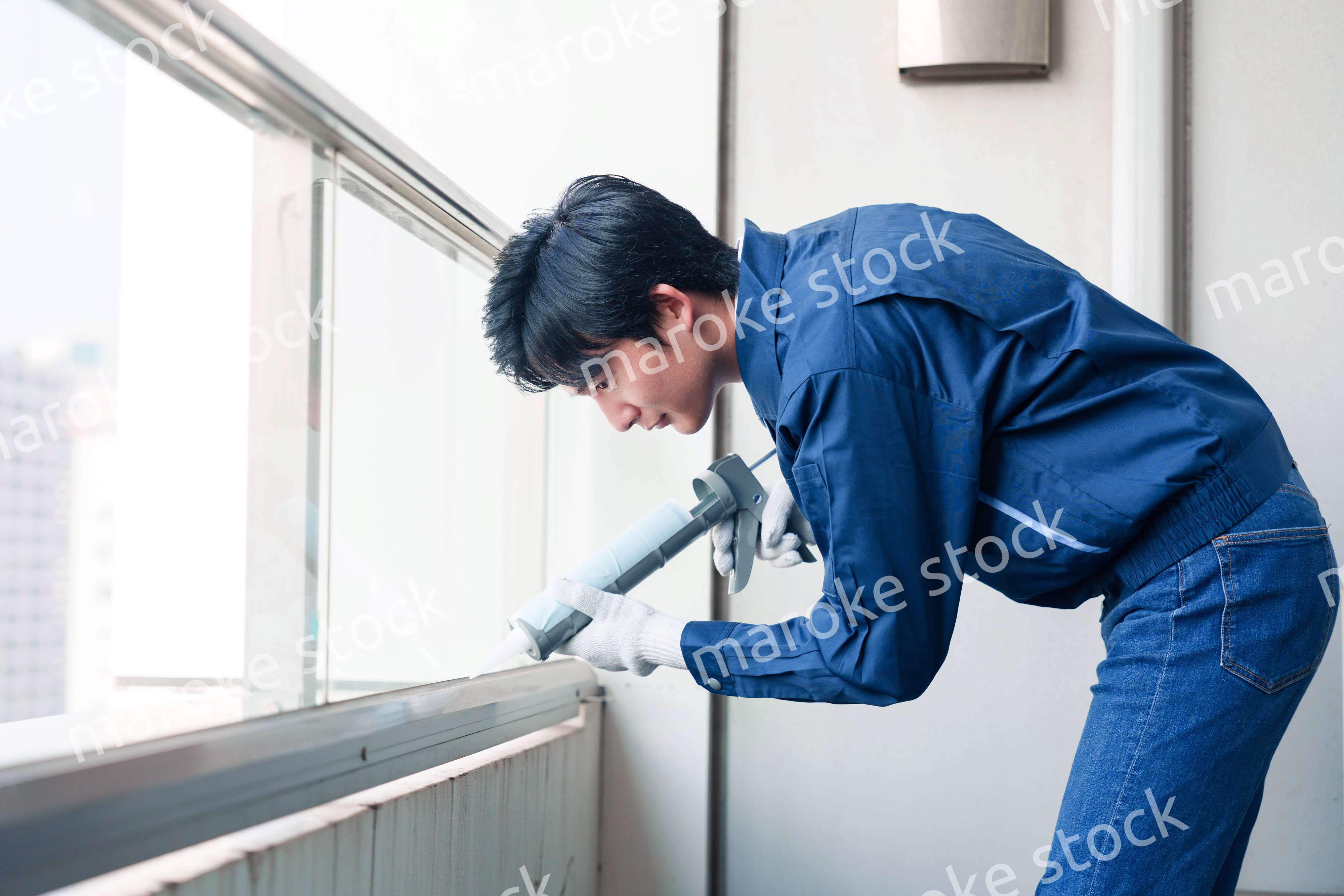 外装工事でコーキング材を塗る作業員の男性