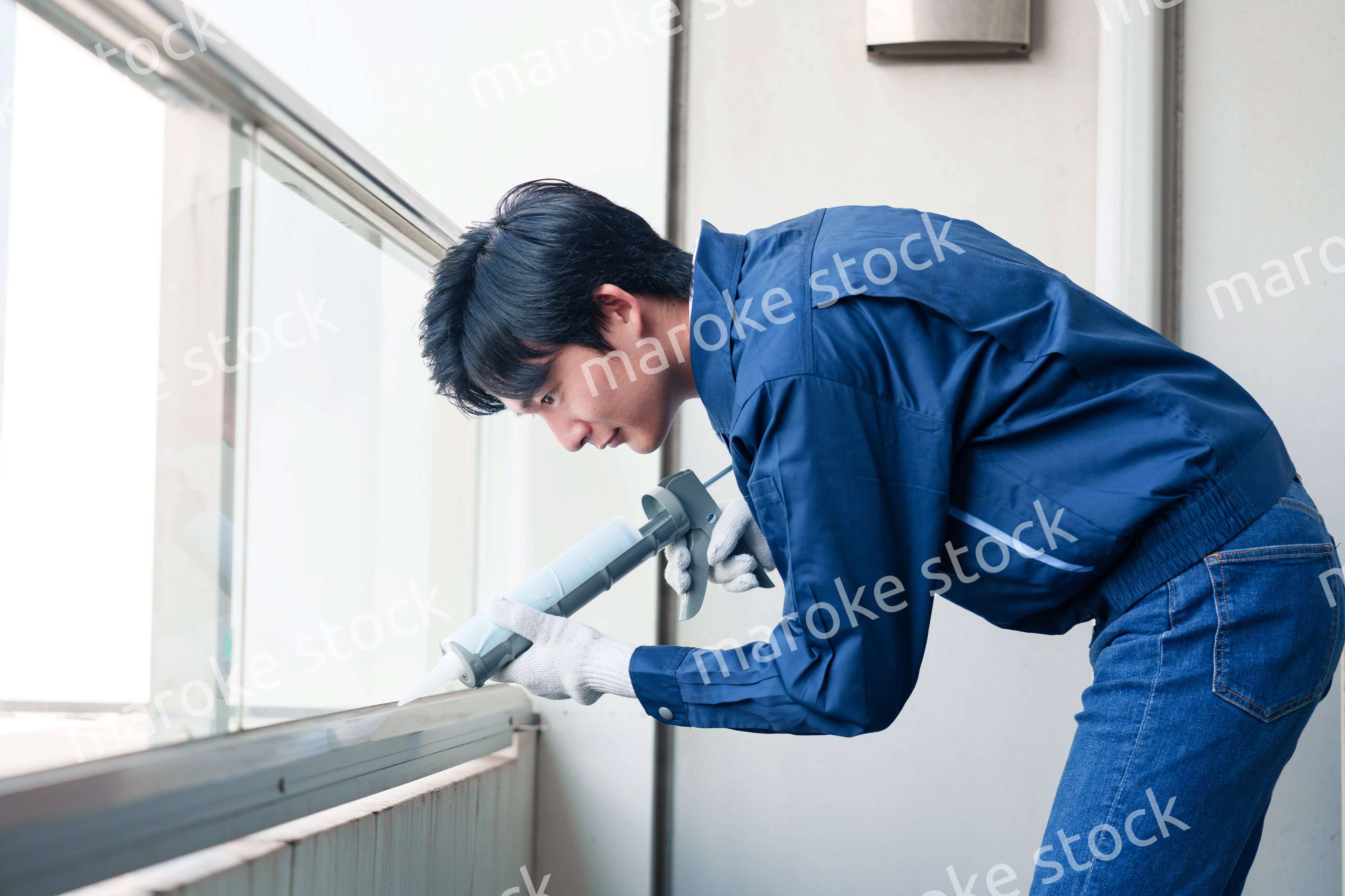 外装工事でコーキング材を塗る作業員の男性