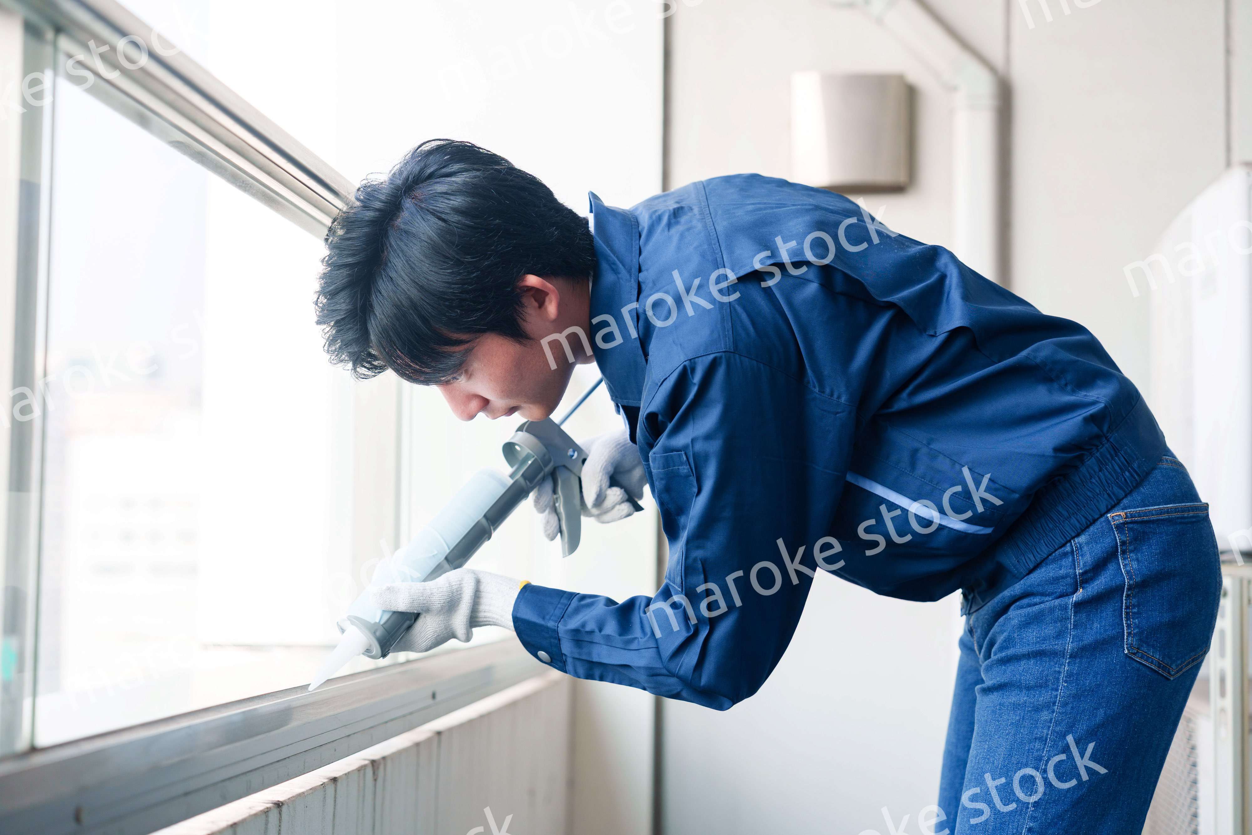 外装工事でコーキング材を塗る作業員の男性