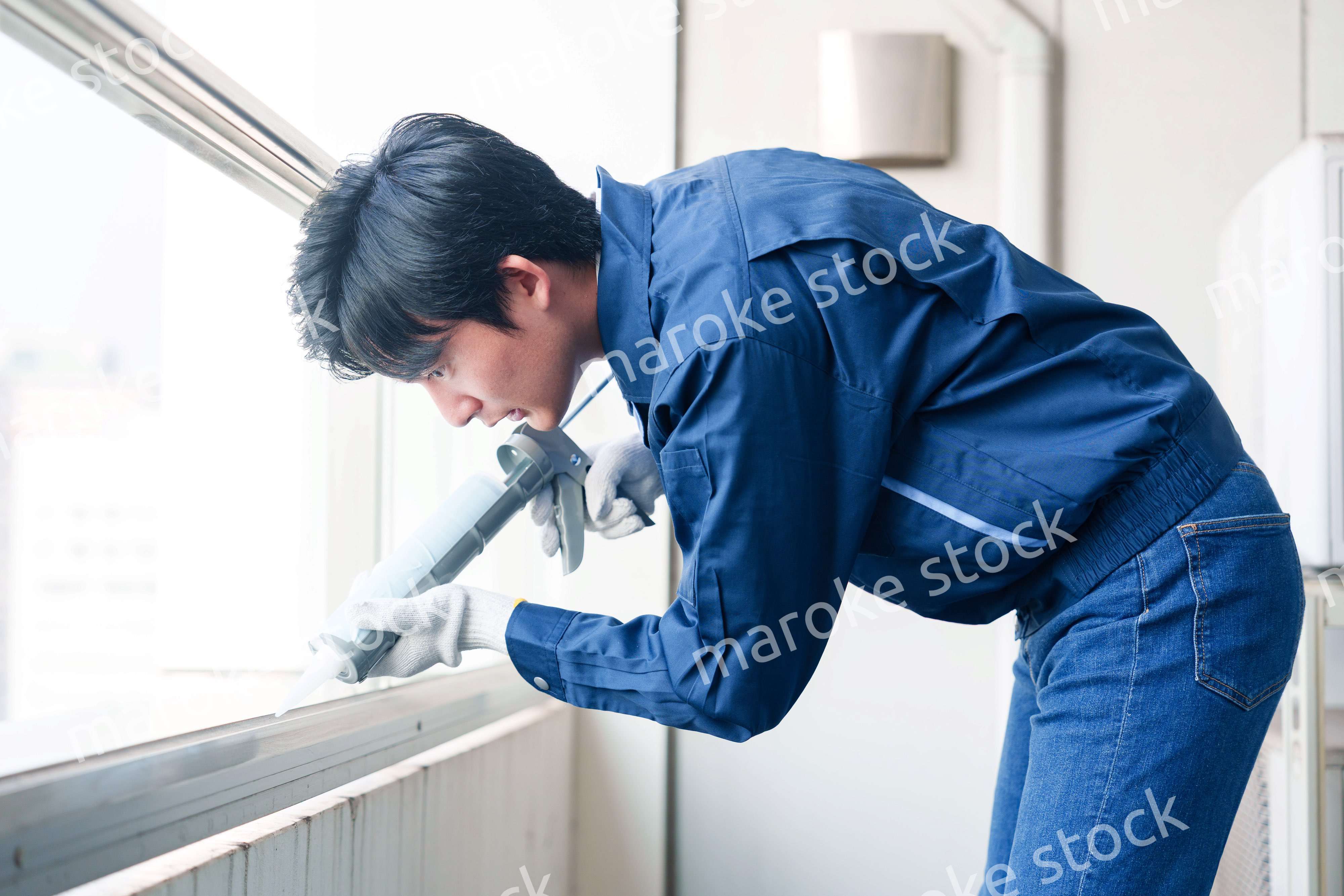 外装工事でコーキング材を塗る作業員の男性