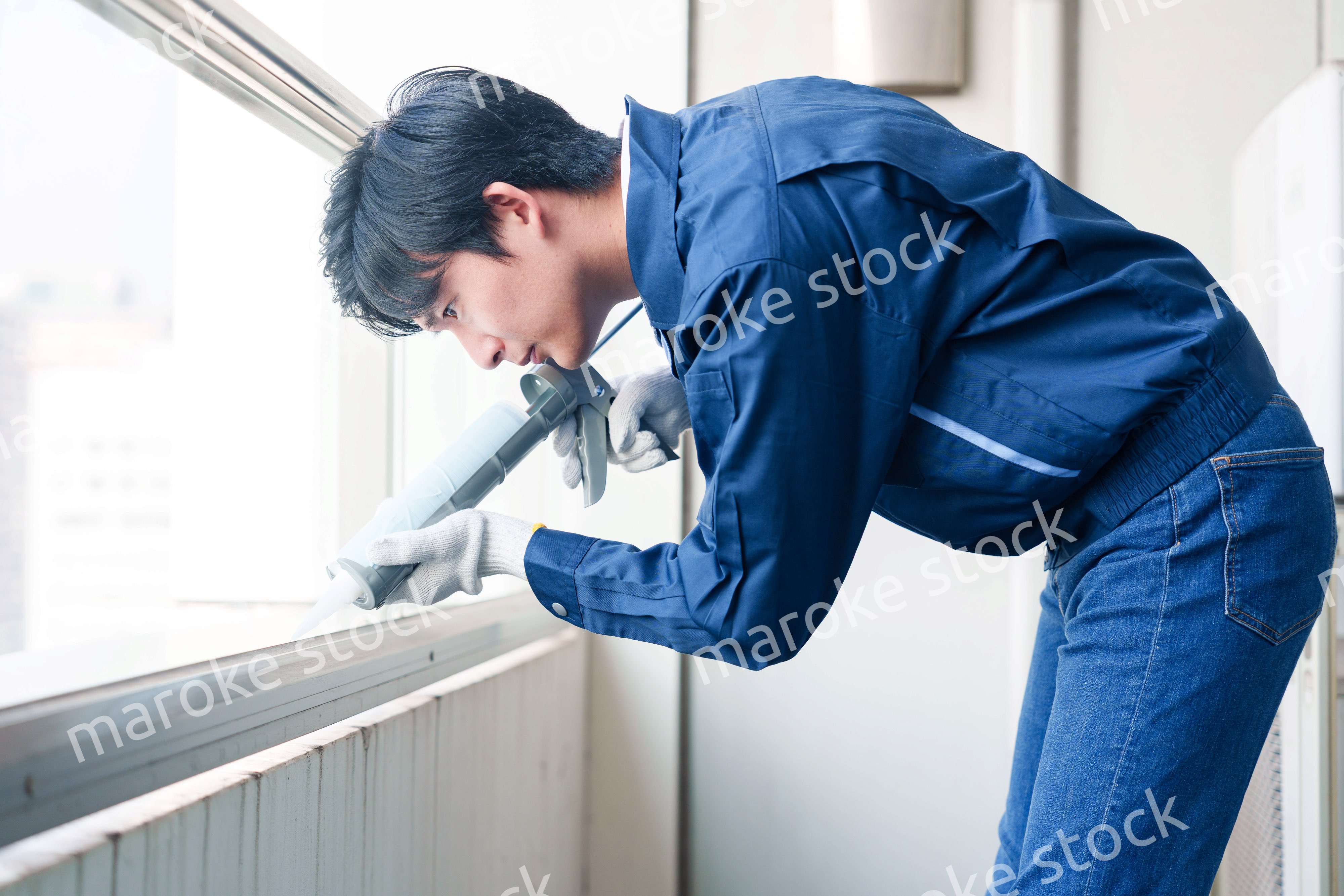 外装工事でコーキング材を塗る作業員の男性