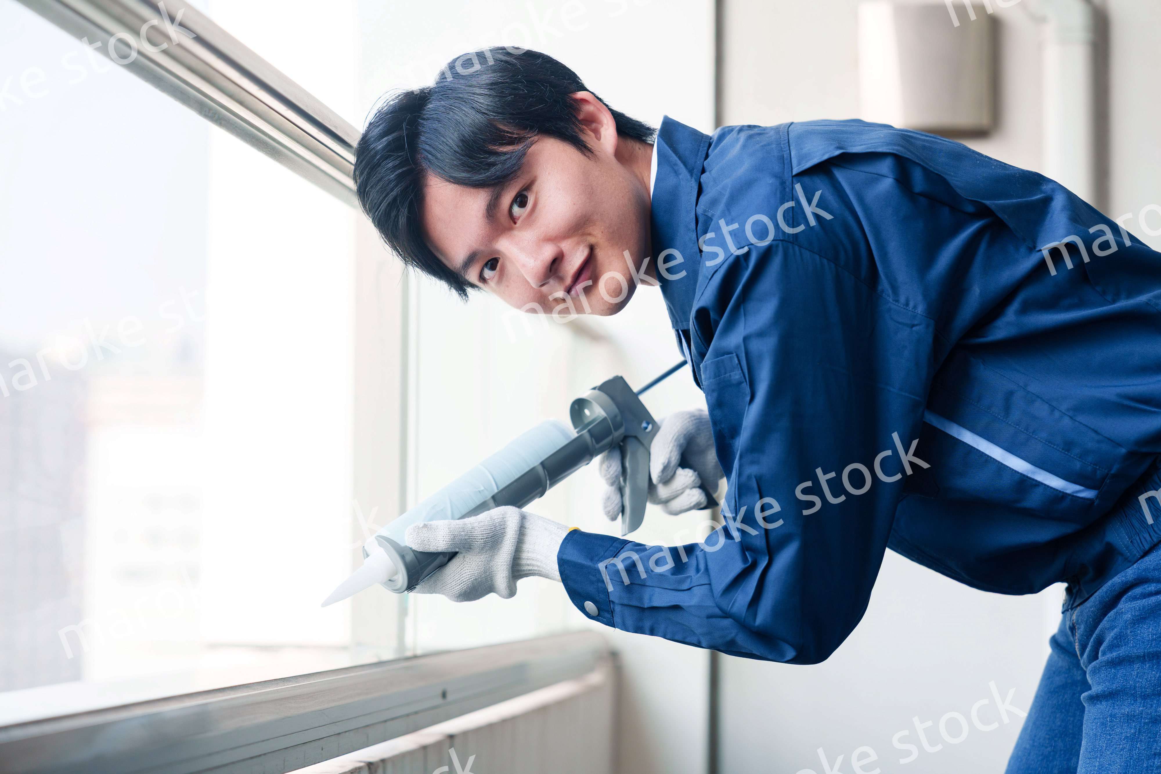 外装工事でコーキング材を塗る作業員の男性