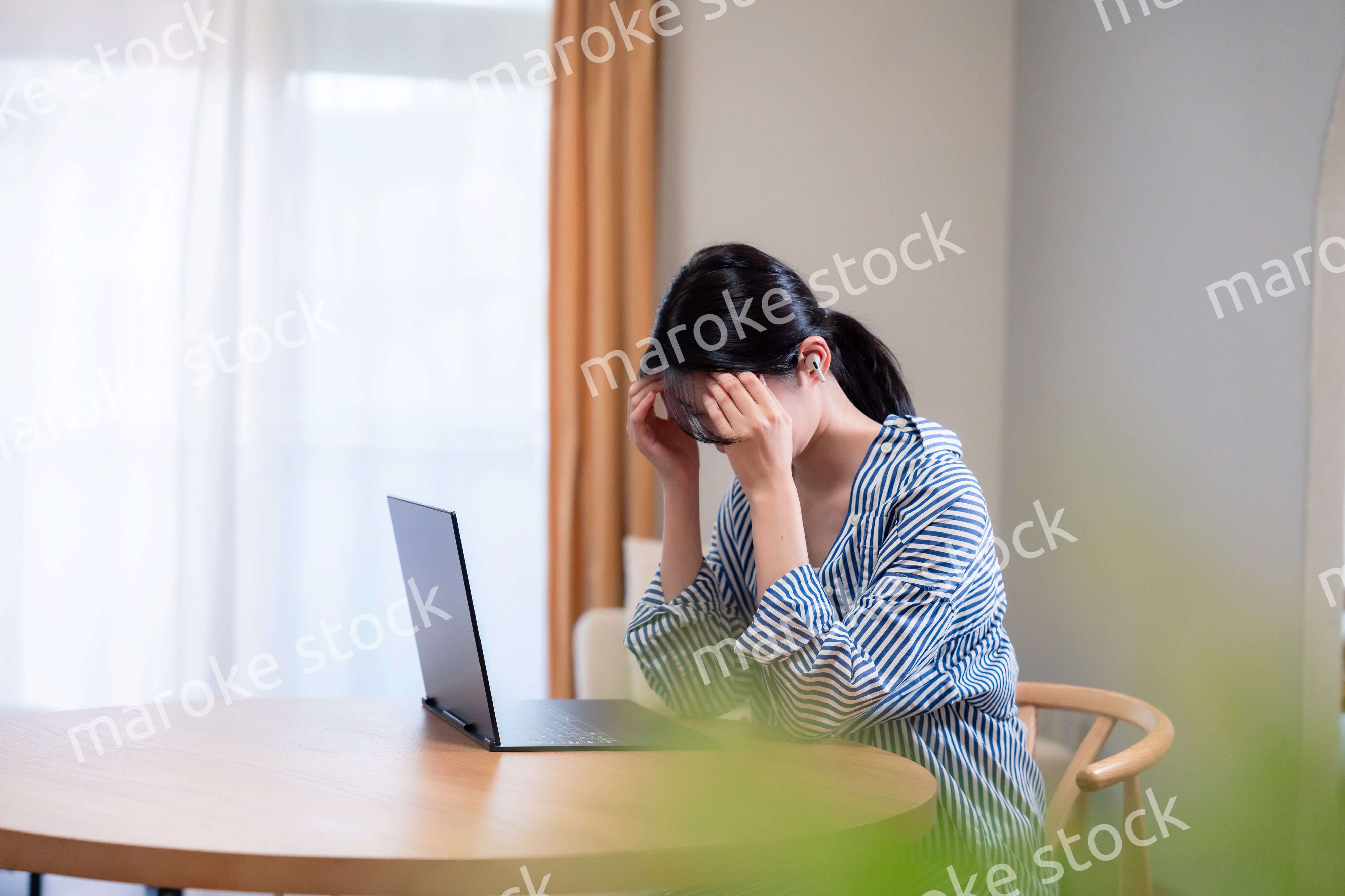 在宅勤務をしながら頭を抱える若い女性