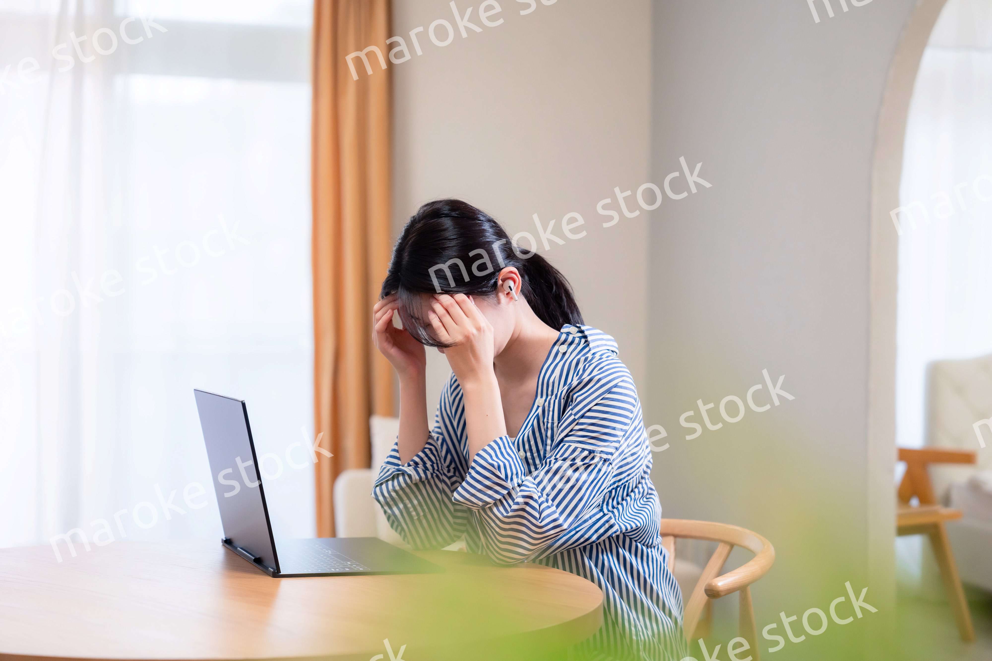 在宅勤務をしながら頭を抱える若い女性