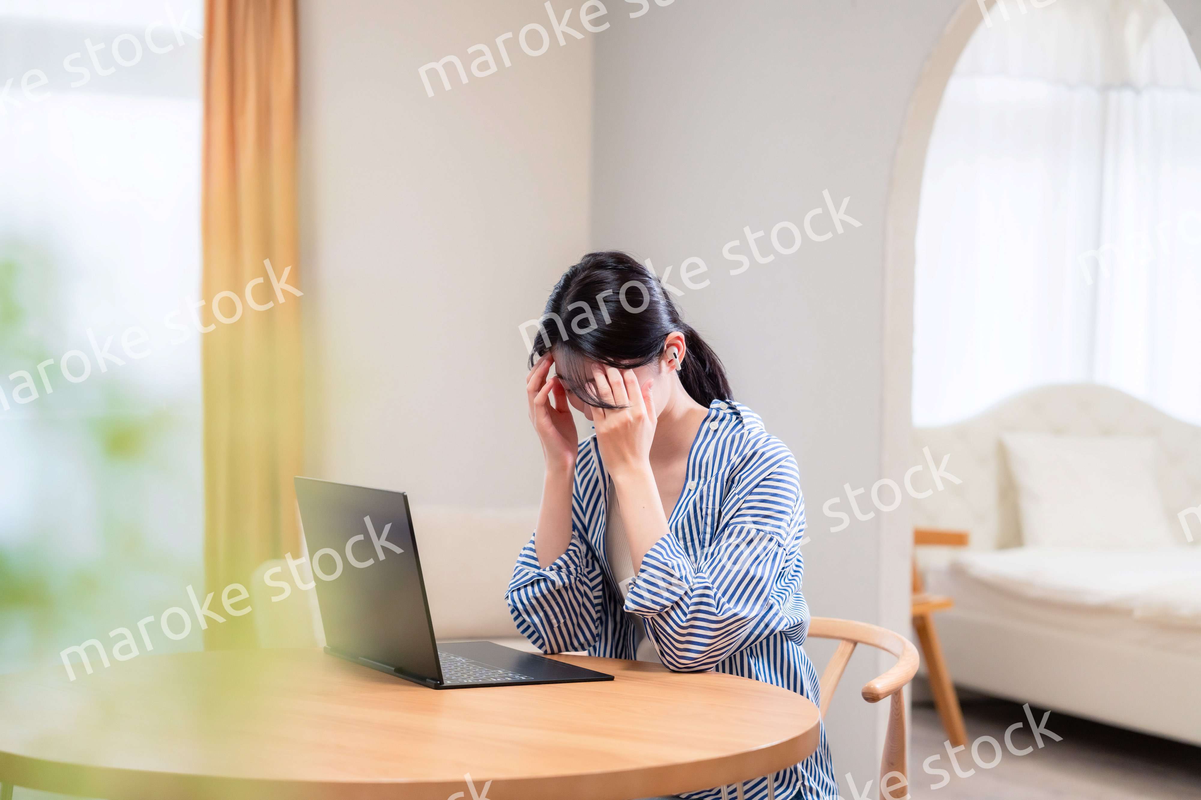 在宅勤務をしながら頭を抱える若い女性