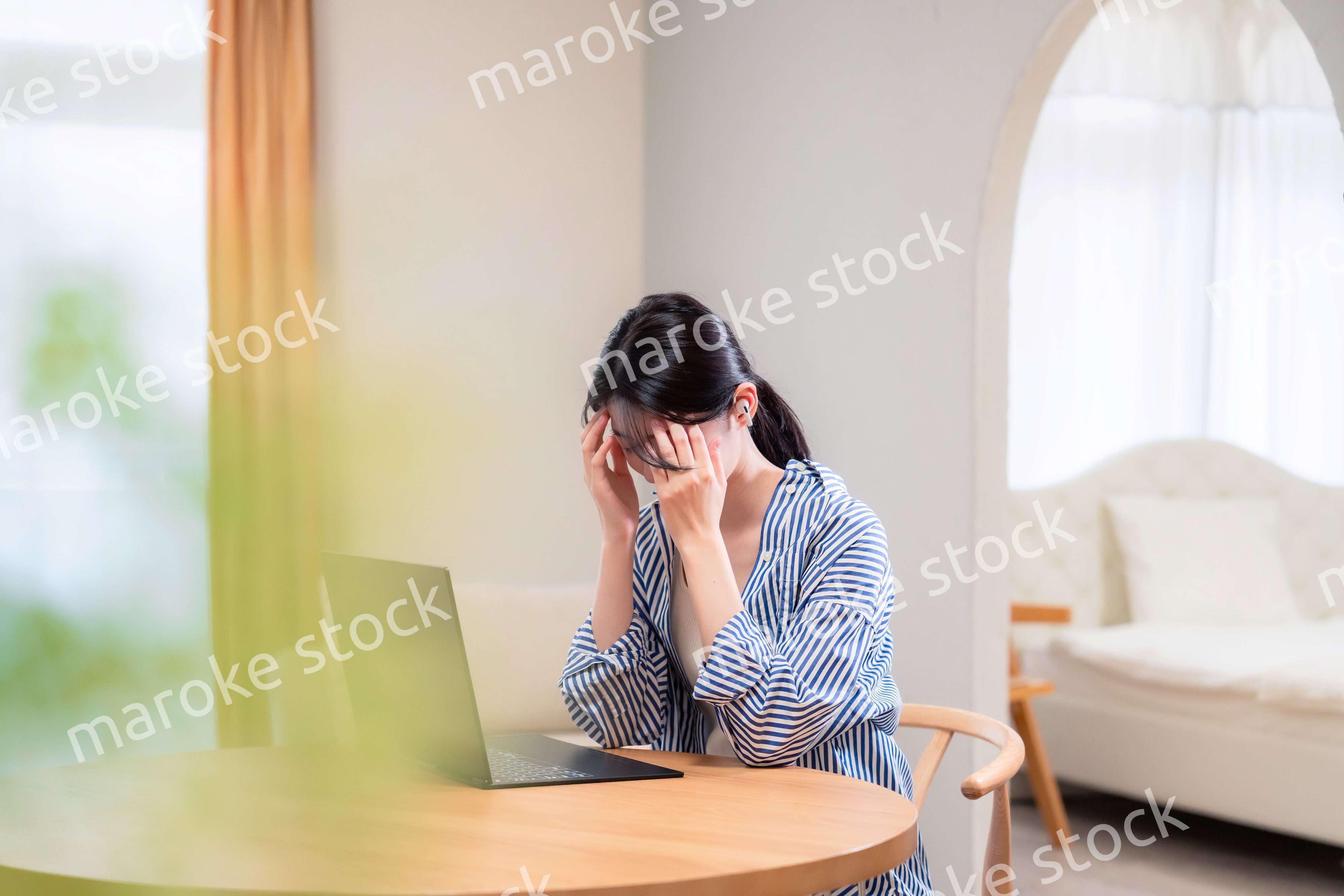 在宅勤務をしながら頭を抱える若い女性