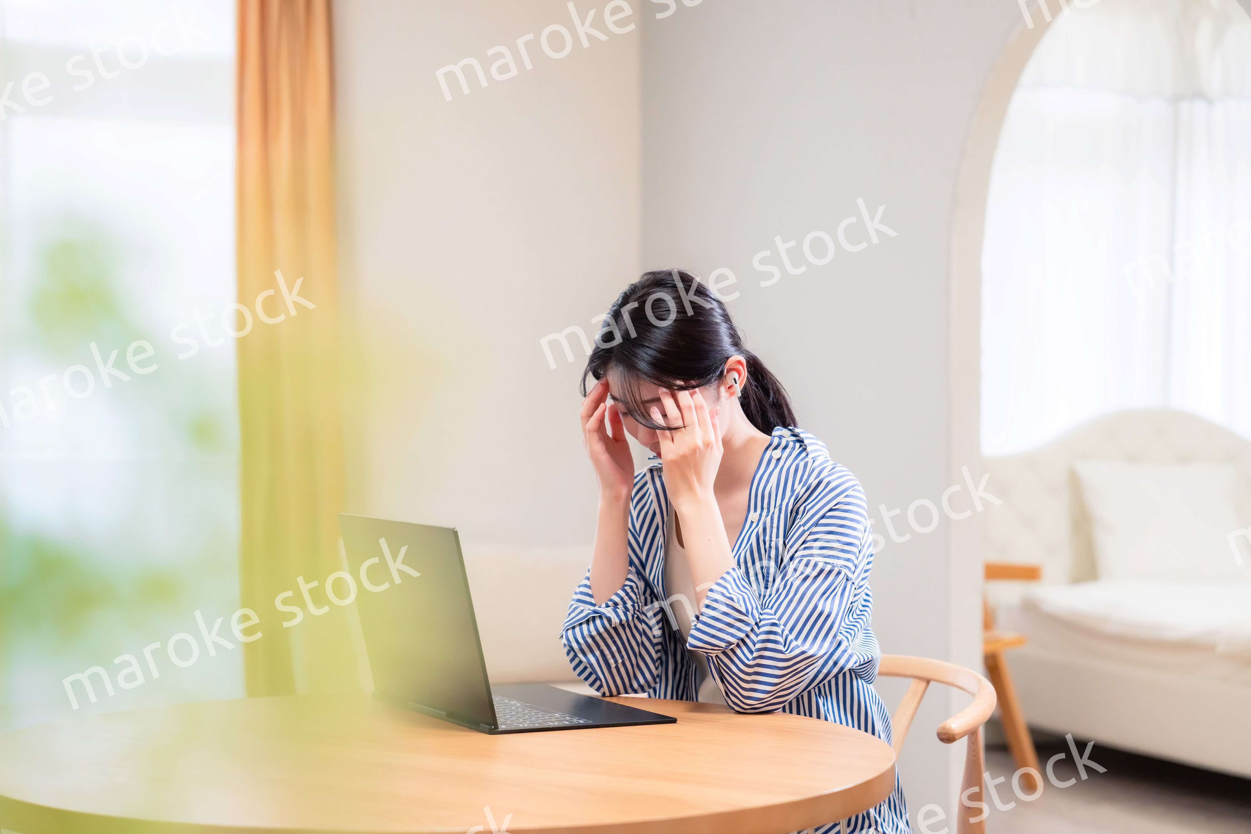 在宅勤務をしながら頭を抱える若い女性