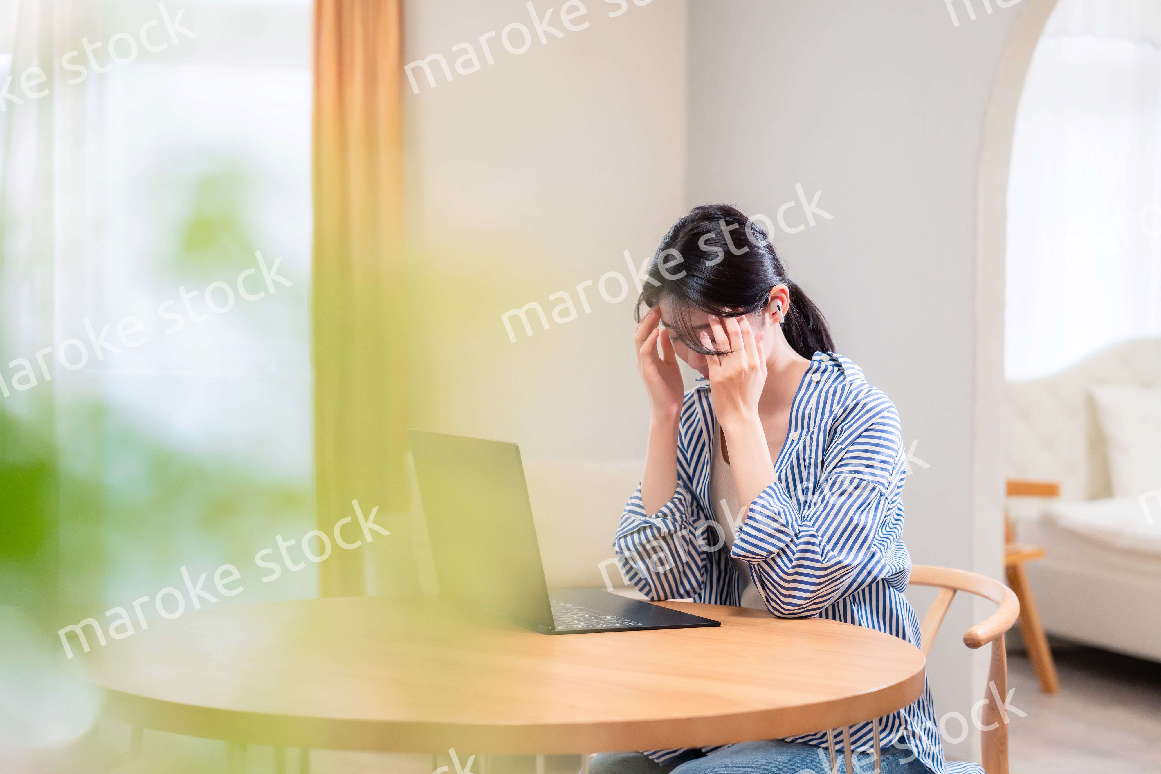 在宅勤務をしながら頭を抱える若い女性