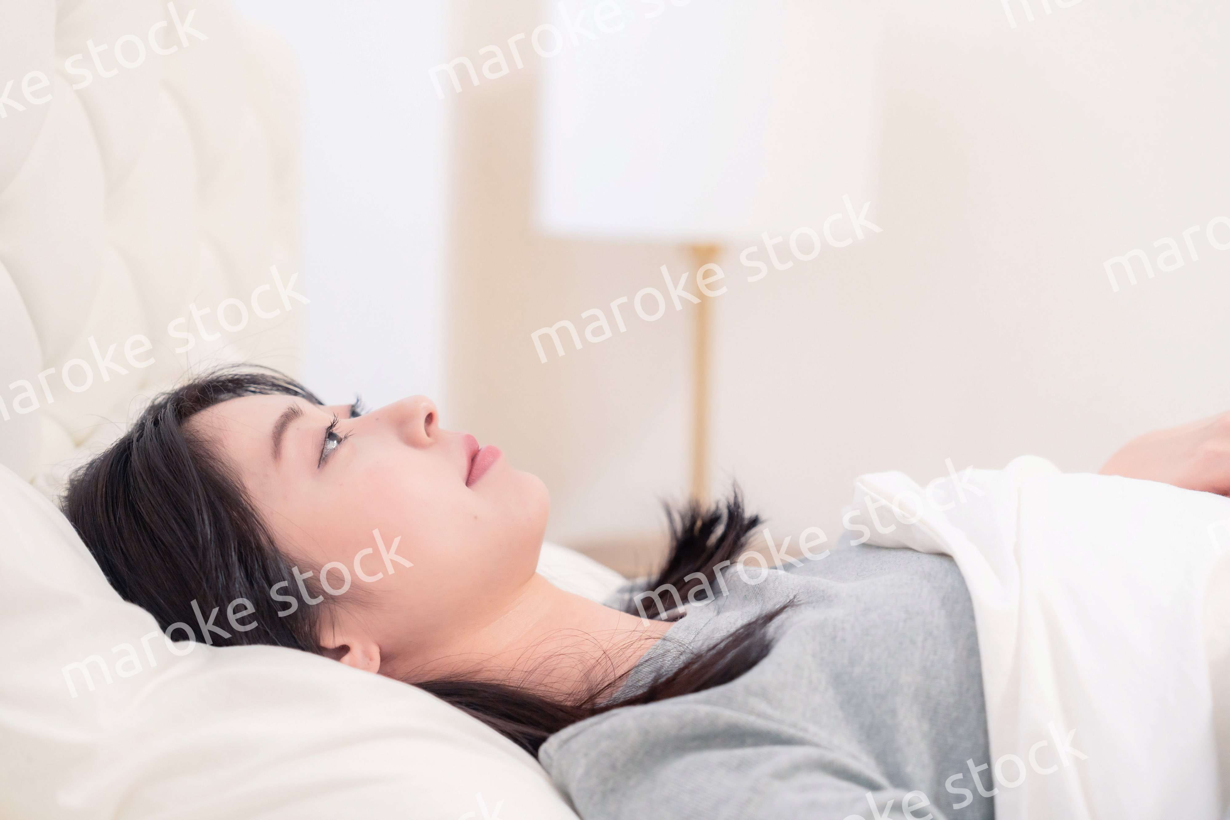 ベッドで寝る若い女性