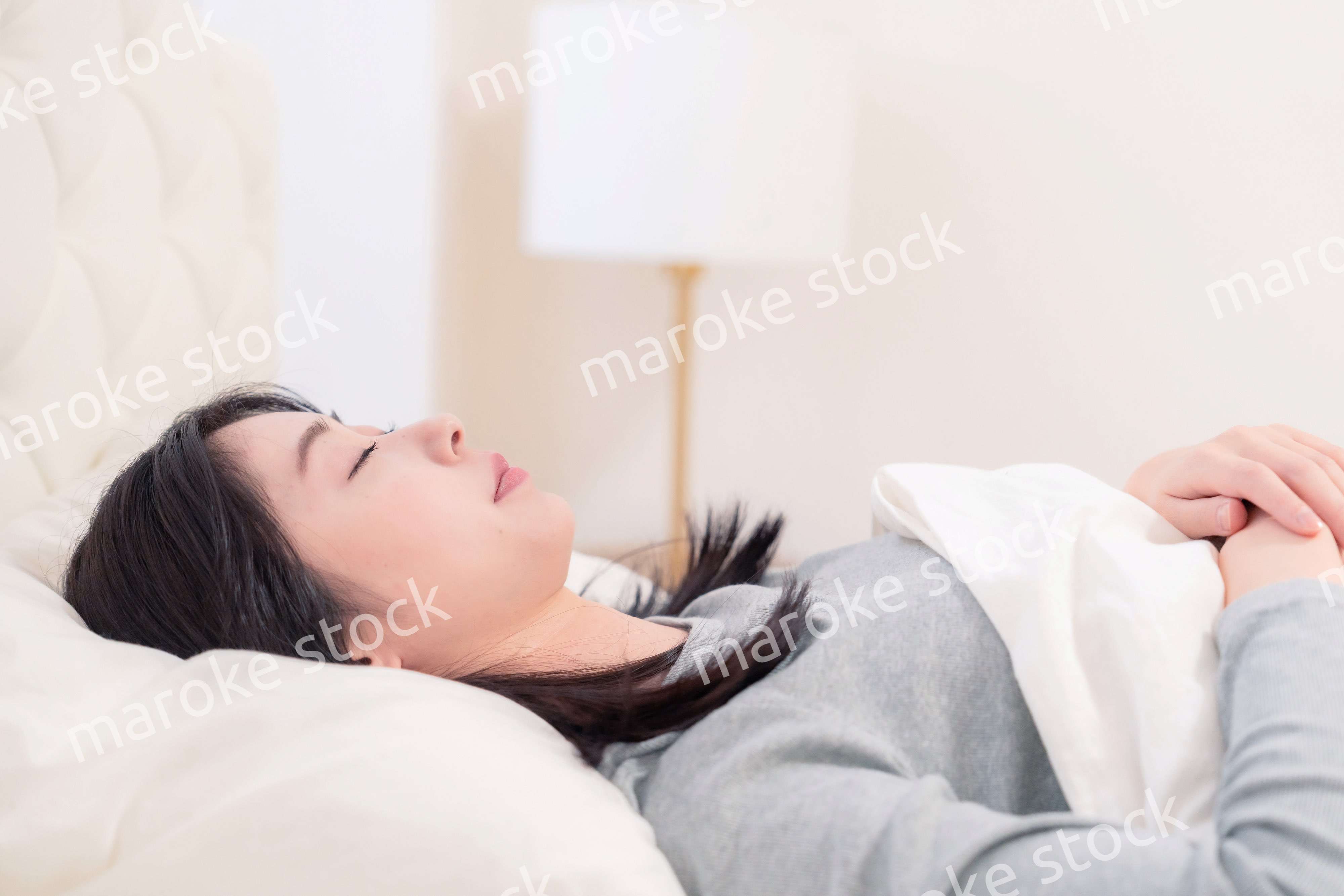 ベッドで寝る若い女性