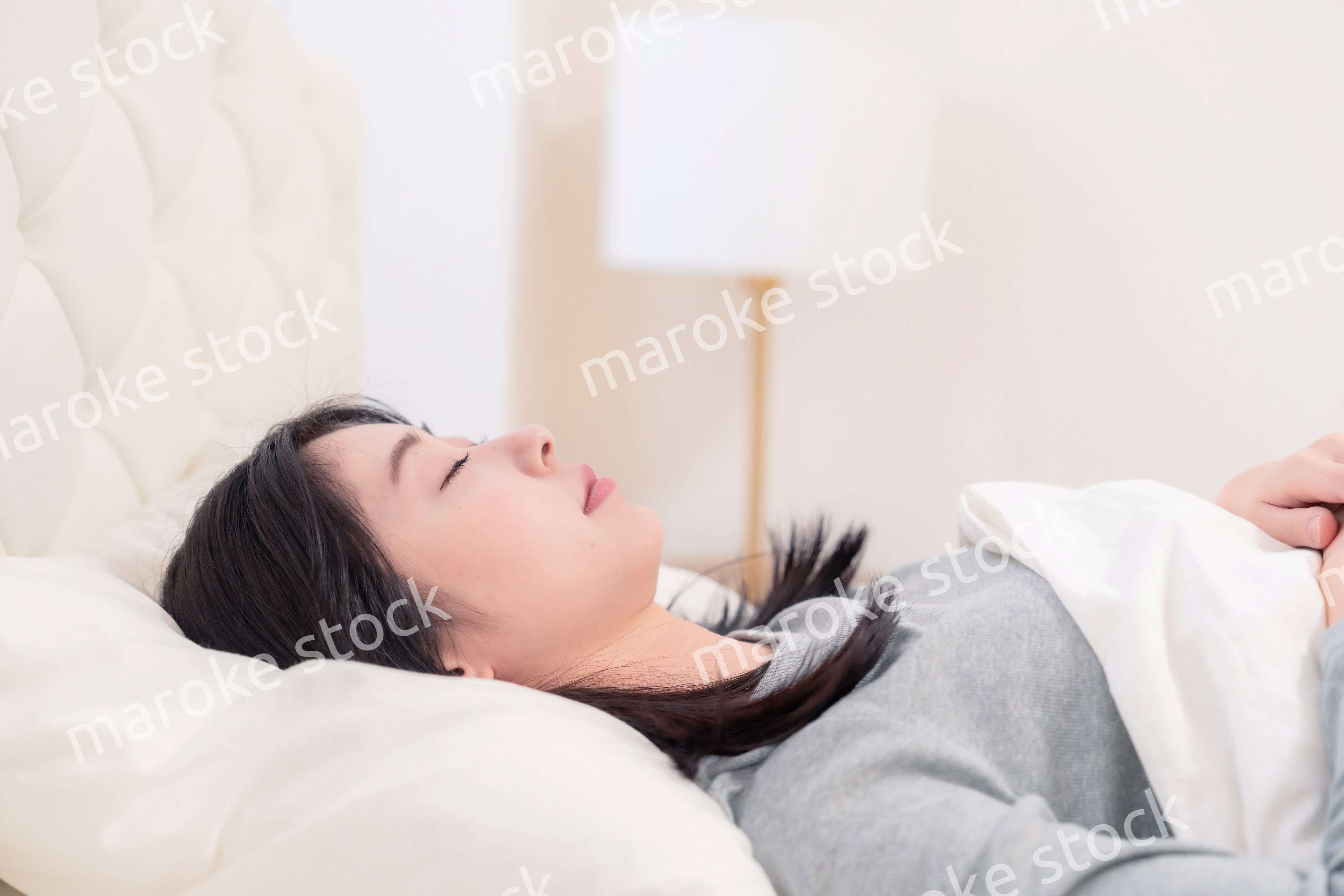 ベッドで寝る若い女性