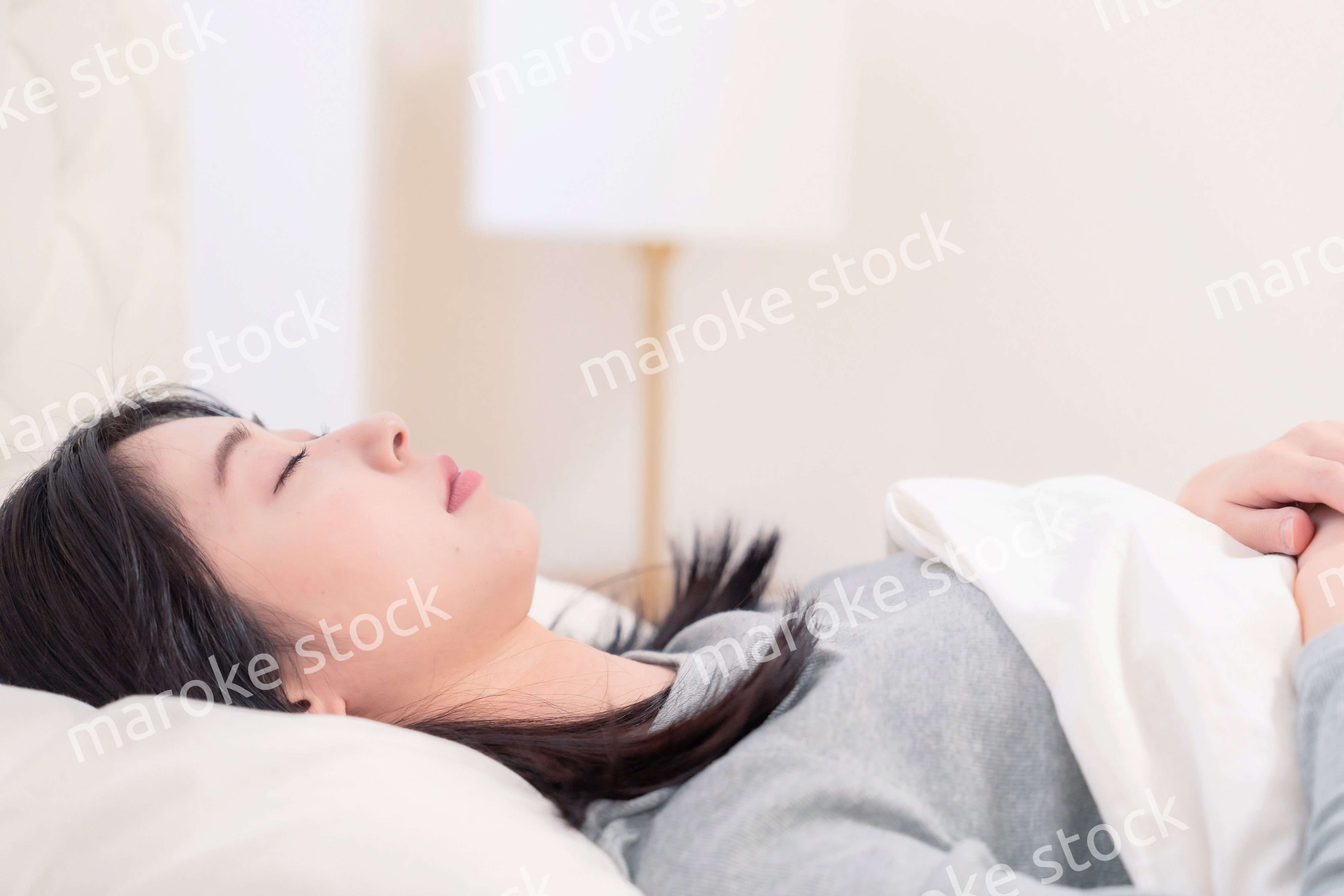 ベッドで寝る若い女性