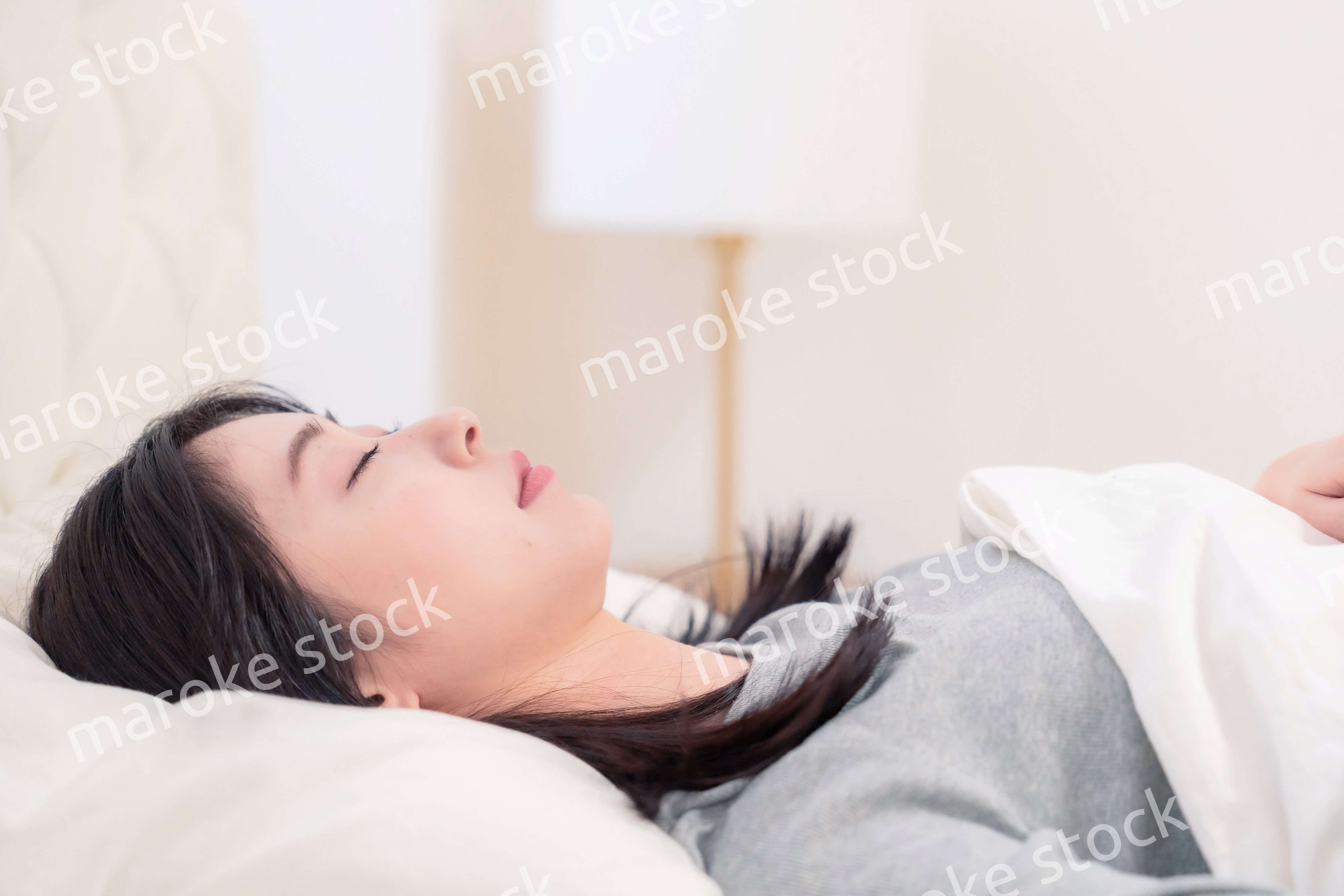 ベッドで寝る若い女性