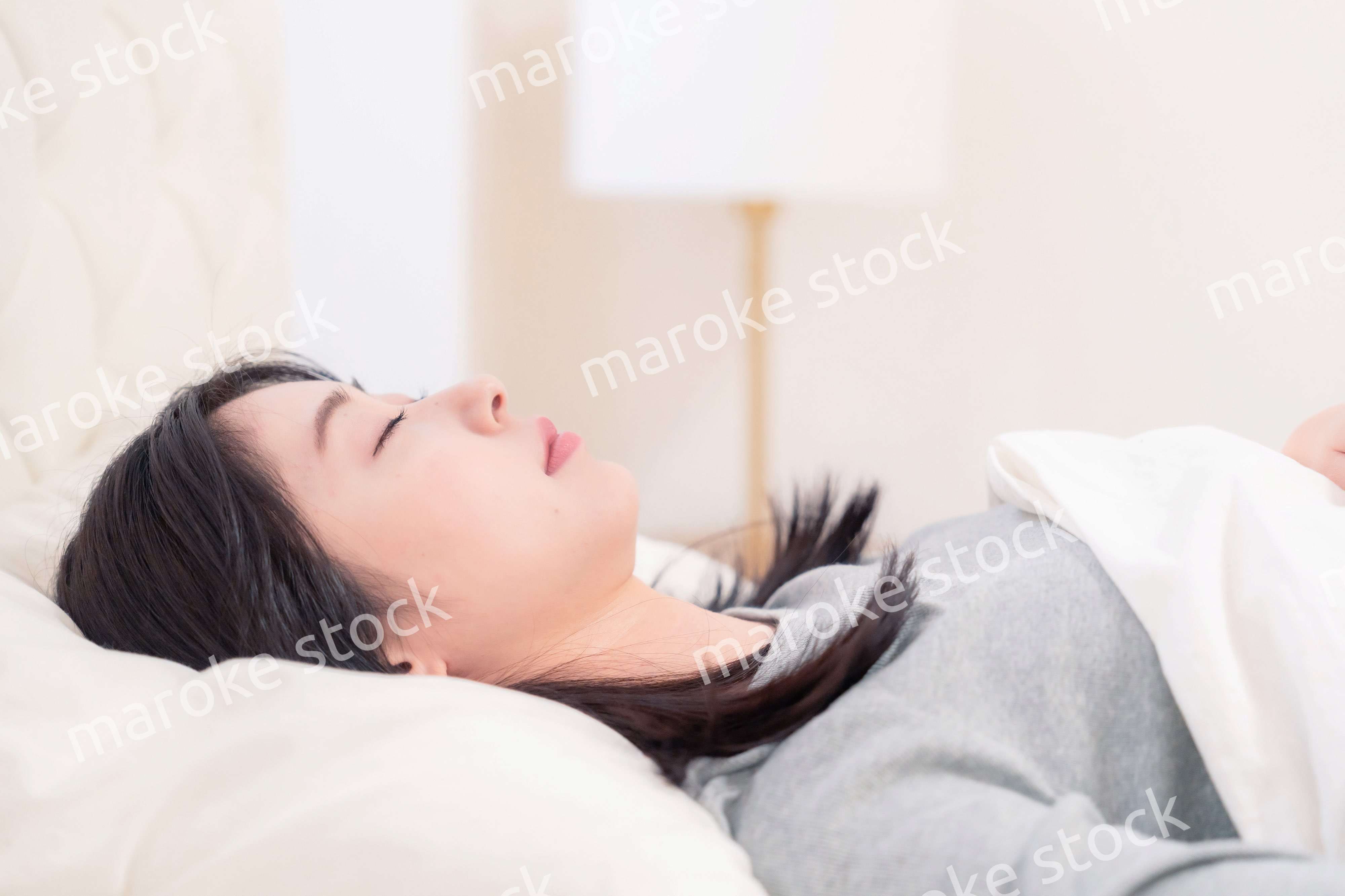 ベッドで寝る若い女性