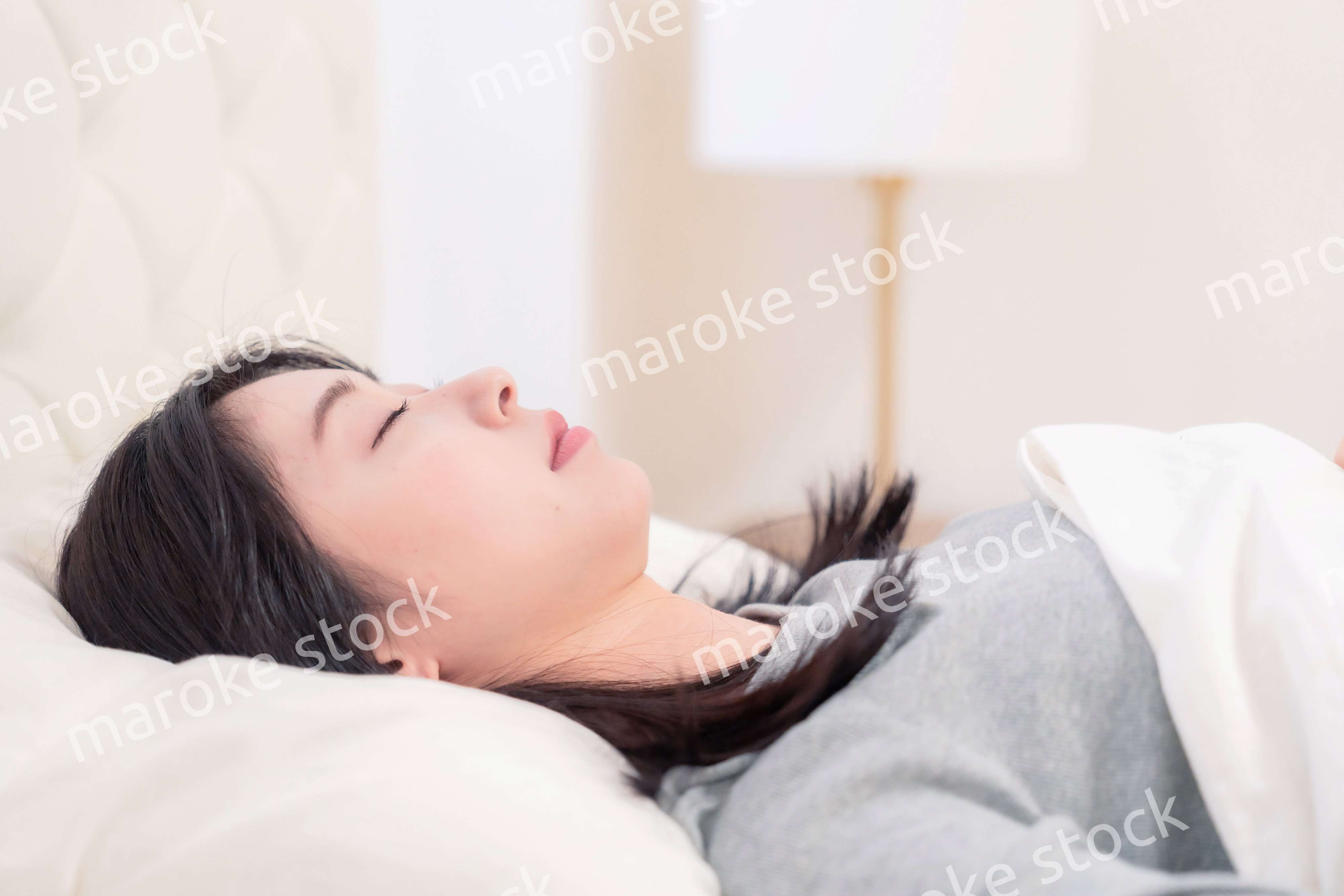 ベッドで寝る若い女性