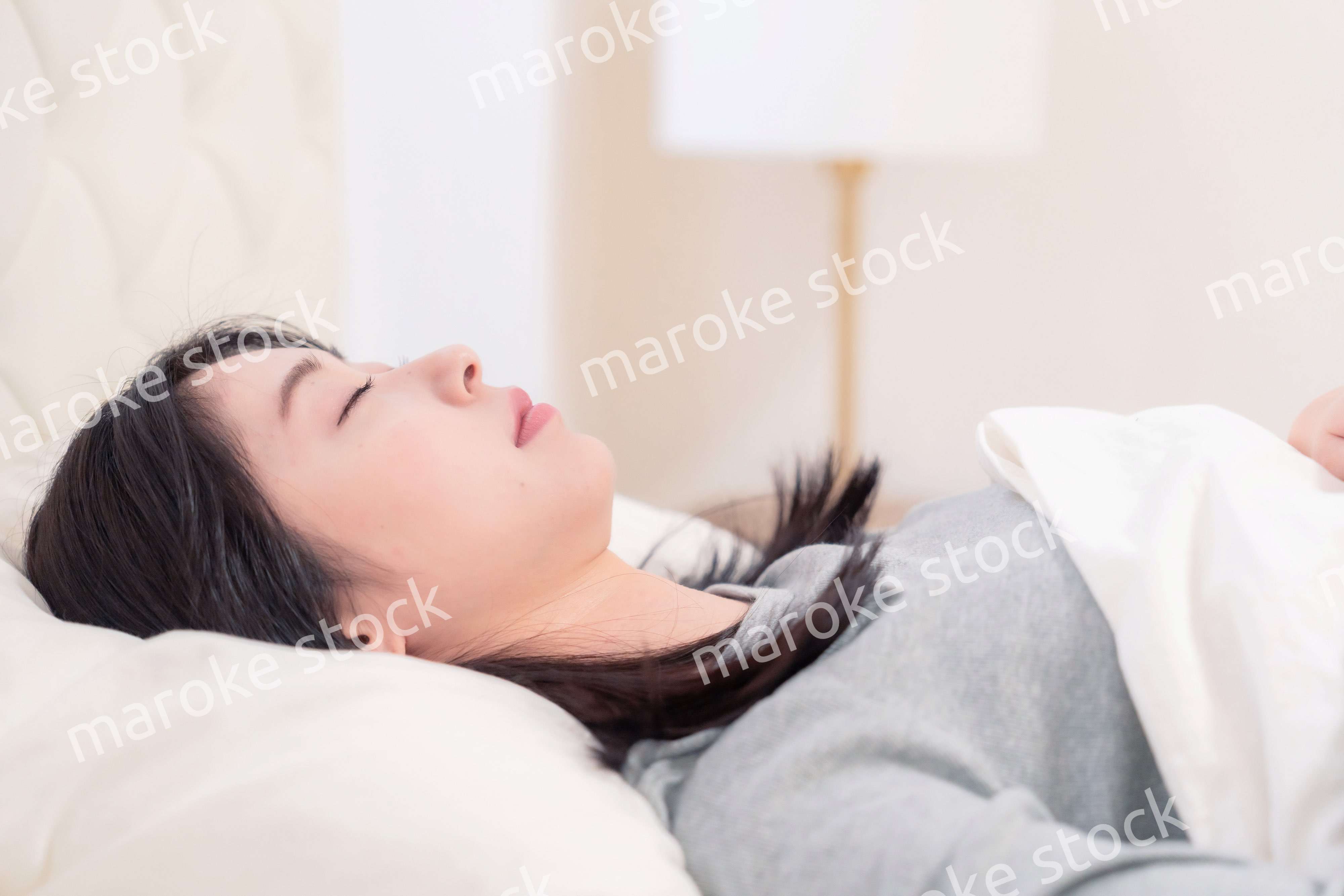 ベッドで寝る若い女性