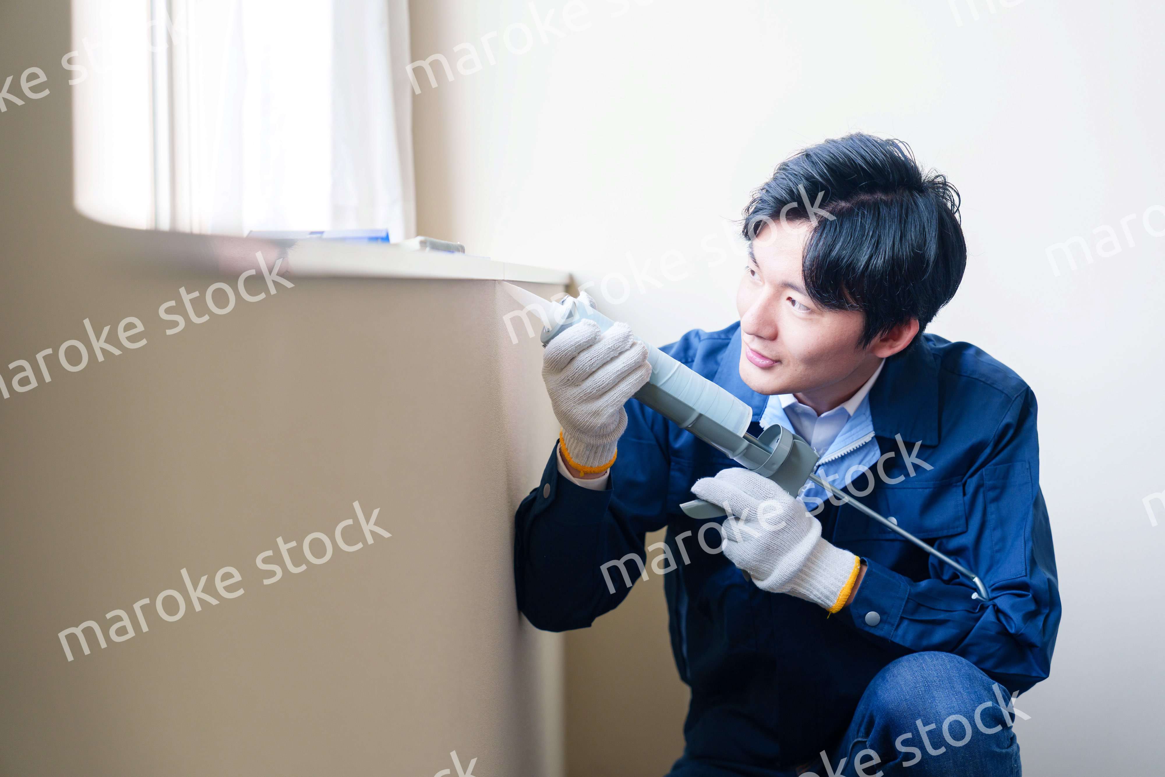 窓にコーキング材を塗る男性の作業員
