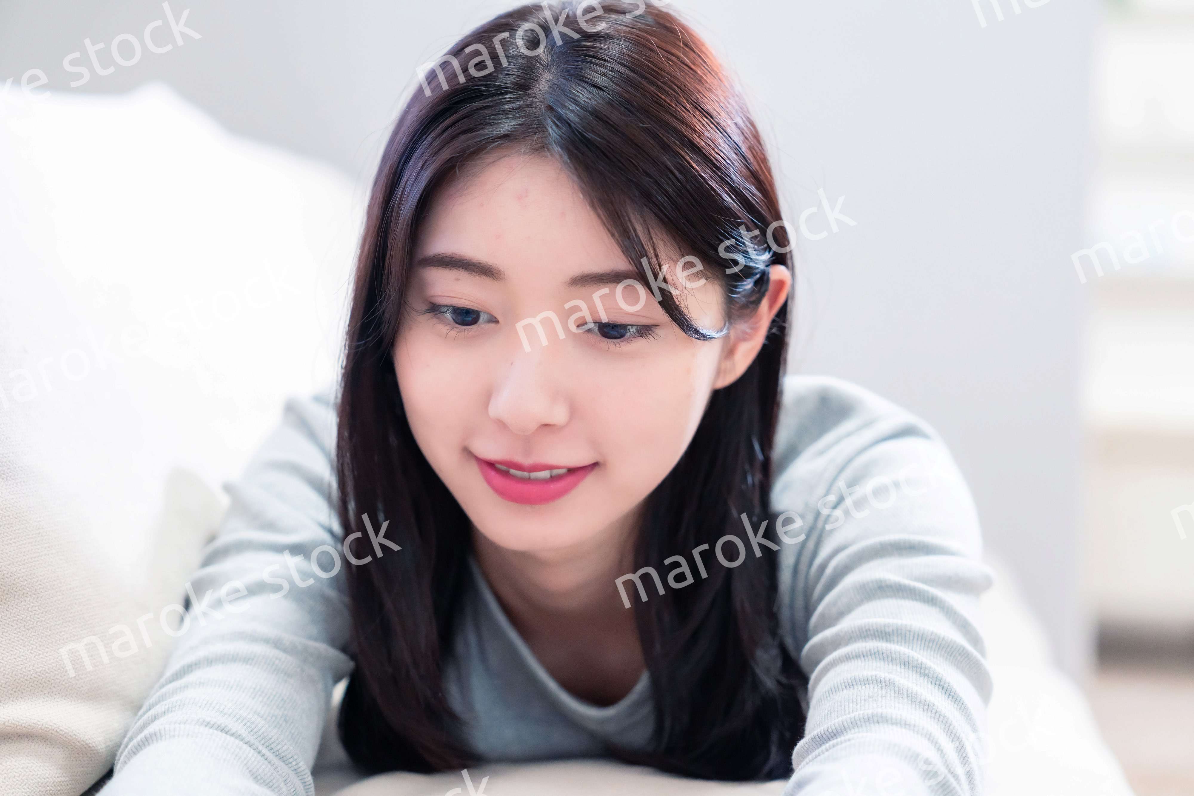 ソファでリラックスをしてスマホを使う若い女性