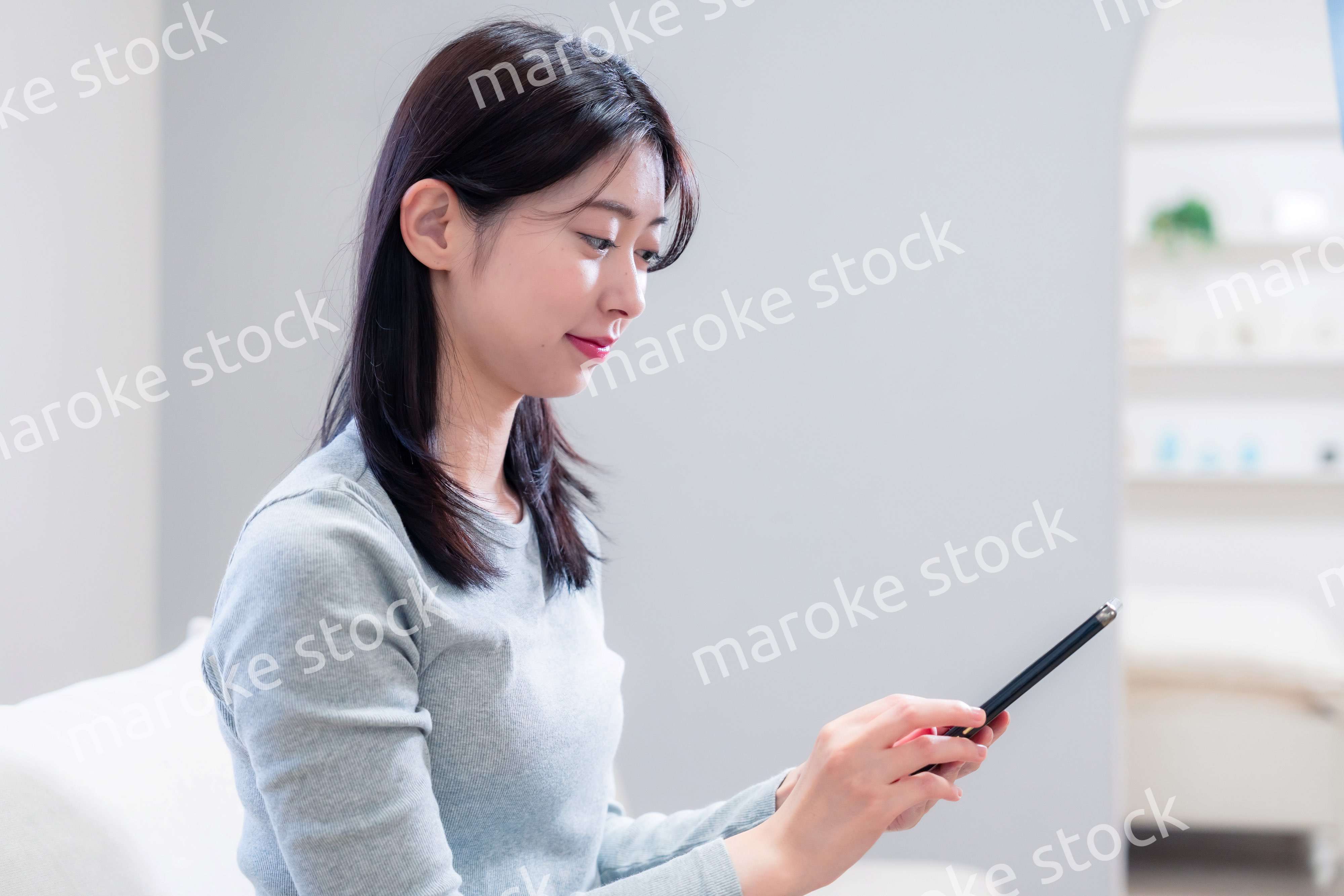 ソファでリラックスをしてスマホを使う若い女性