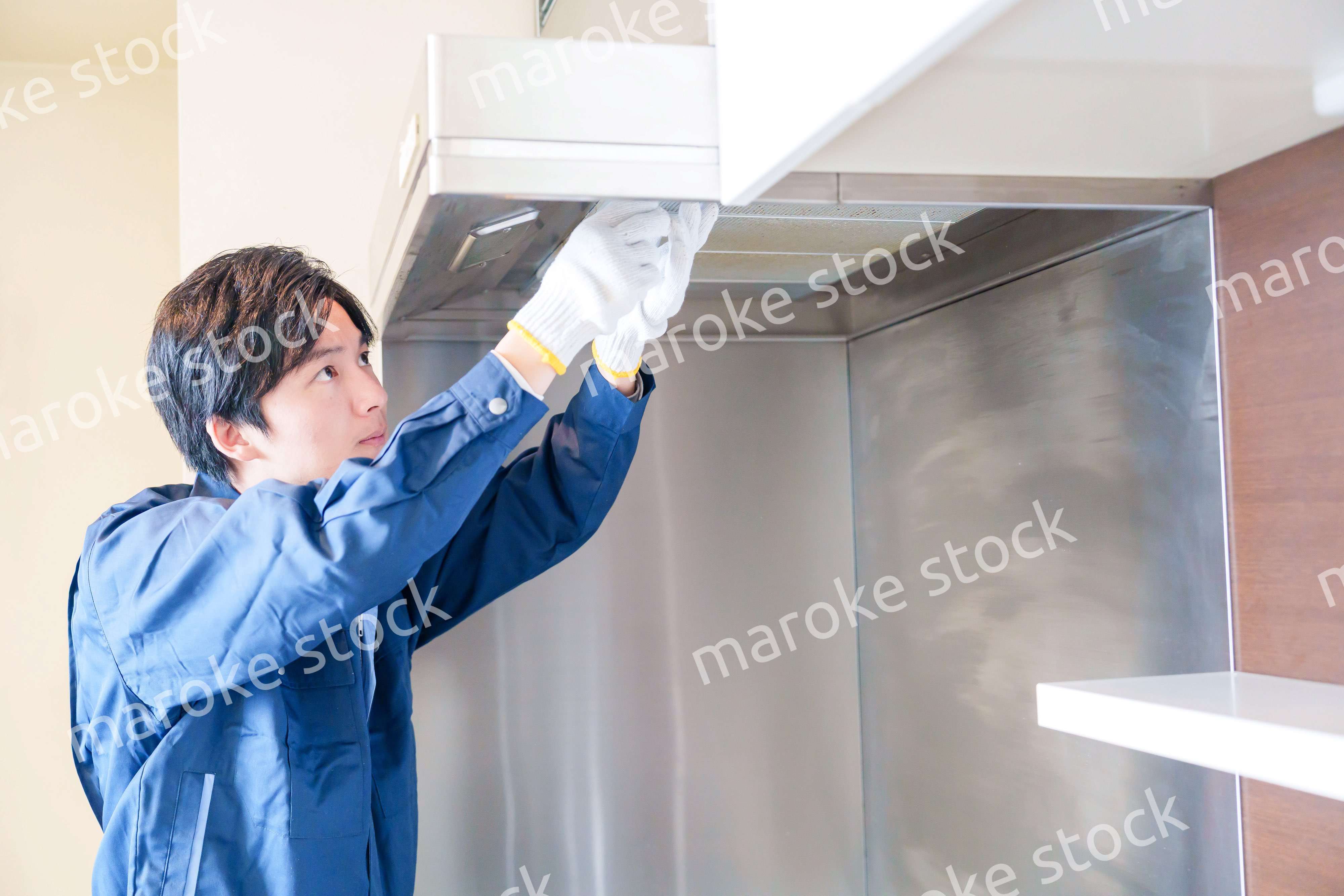 レンジフードのクリーニングをする男性の作業員