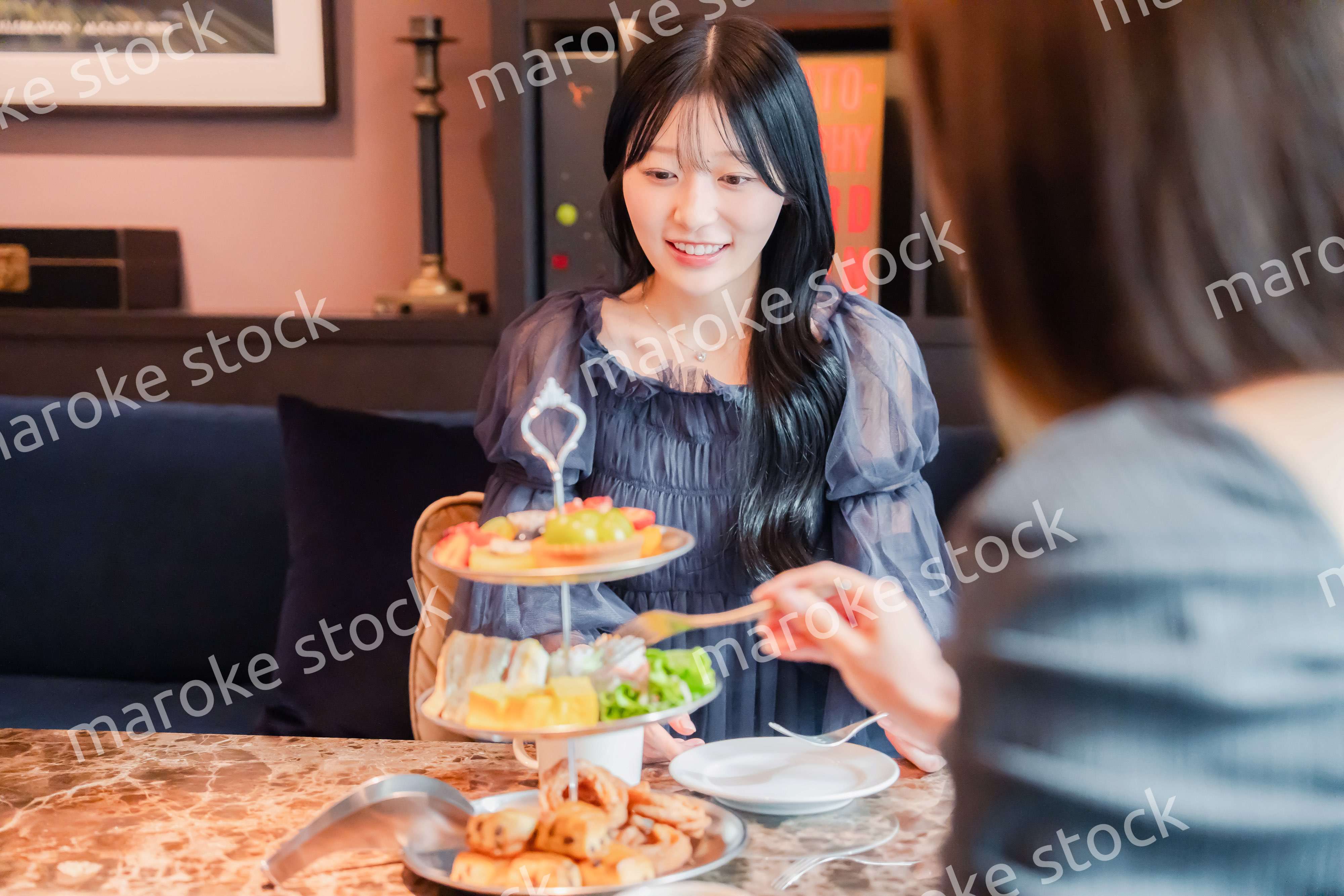 ホテルでアフタヌーンティーを楽しむ若い二人の女性