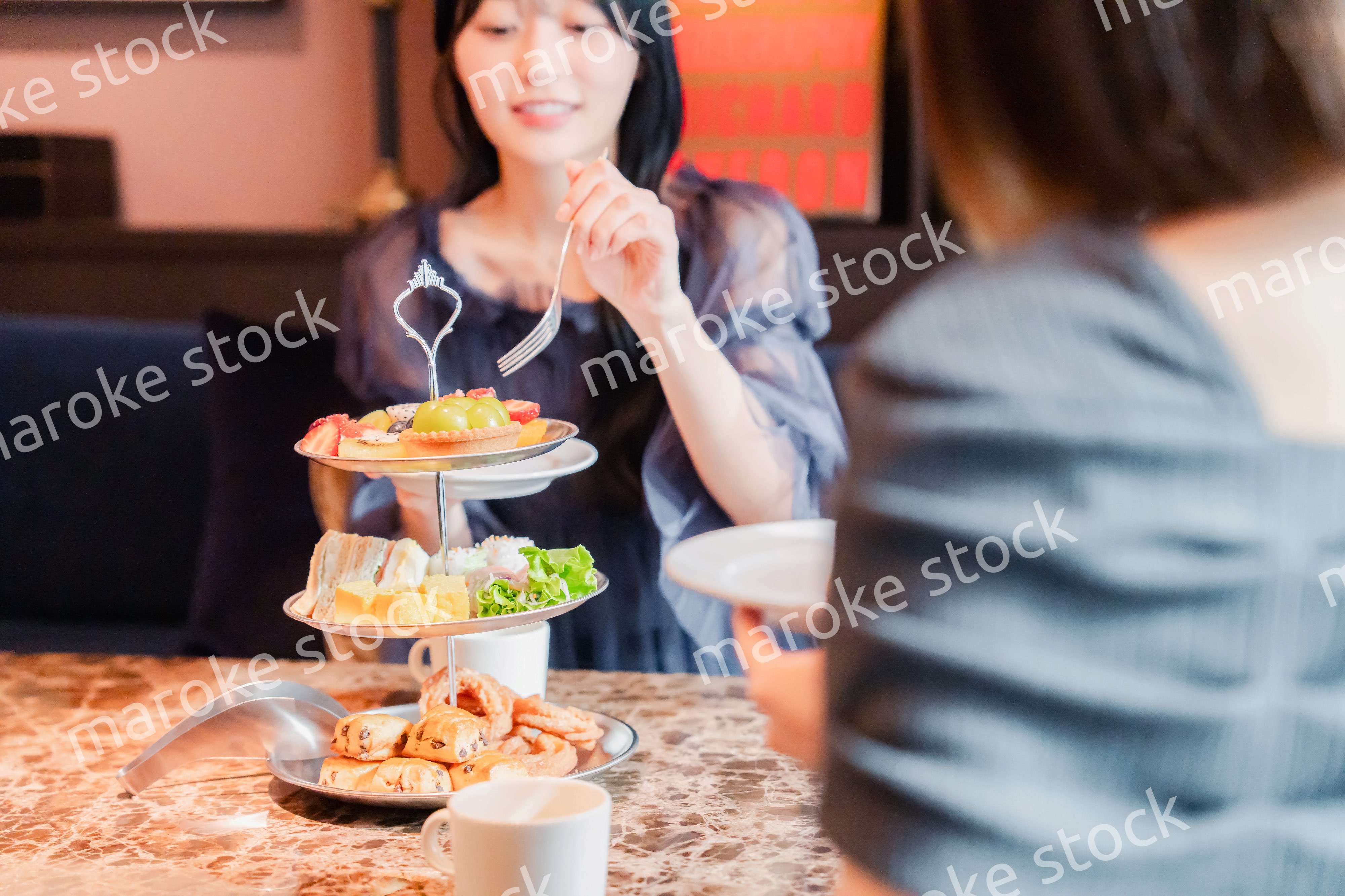 ホテルでアフタヌーンティーを楽しむ若い二人の女性