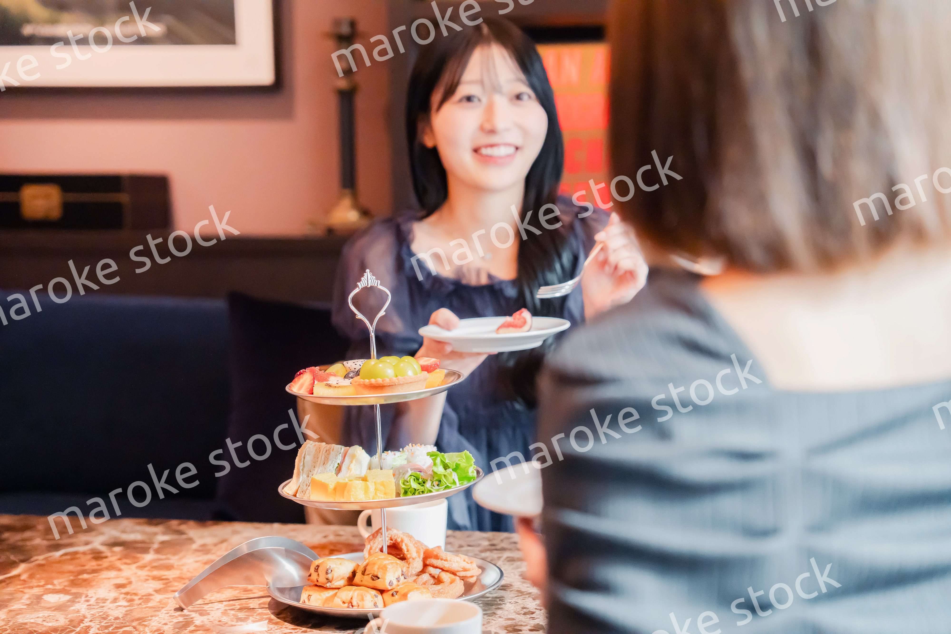 ホテルでアフタヌーンティーを楽しむ若い二人の女性