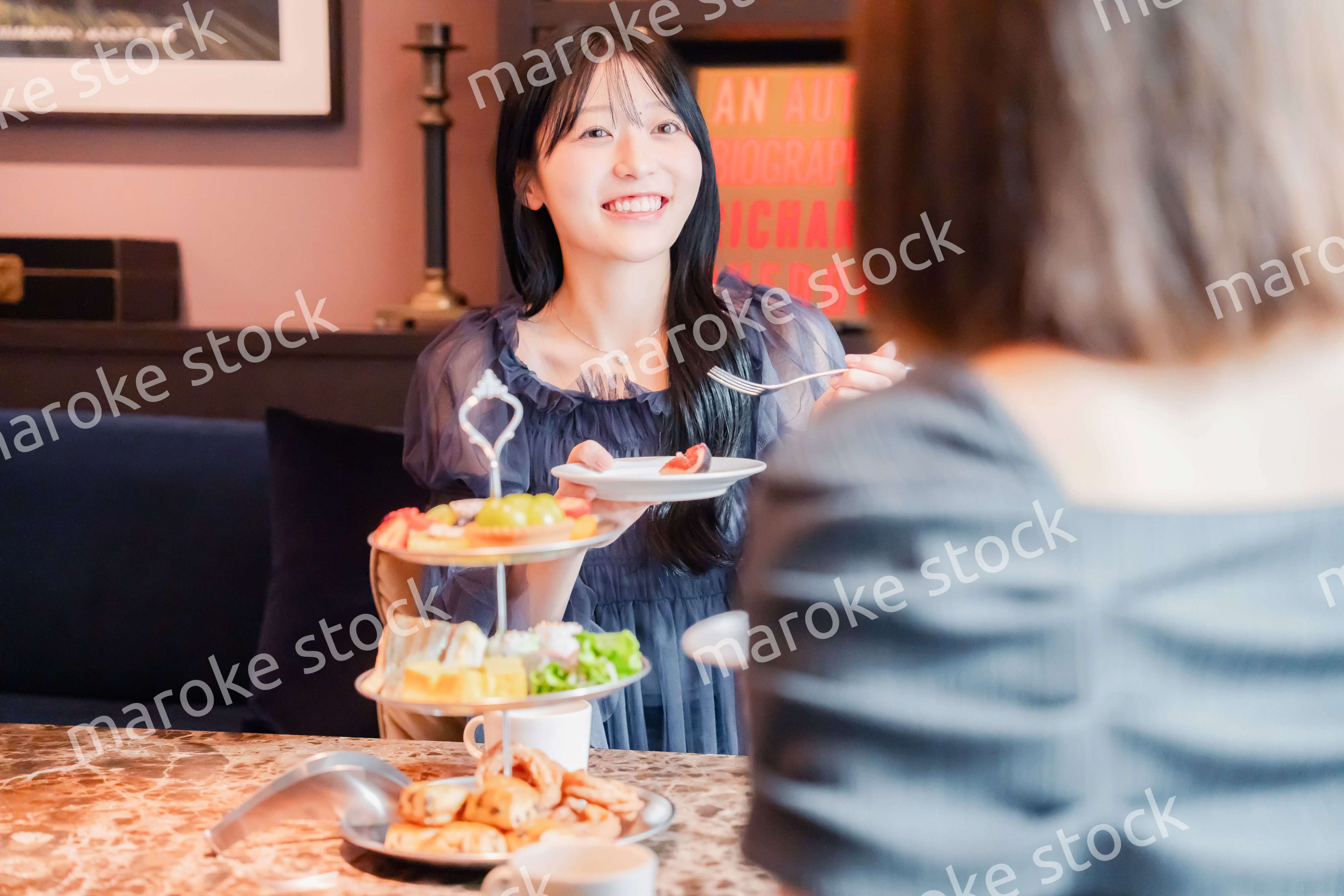 ホテルでアフタヌーンティーを楽しむ若い二人の女性