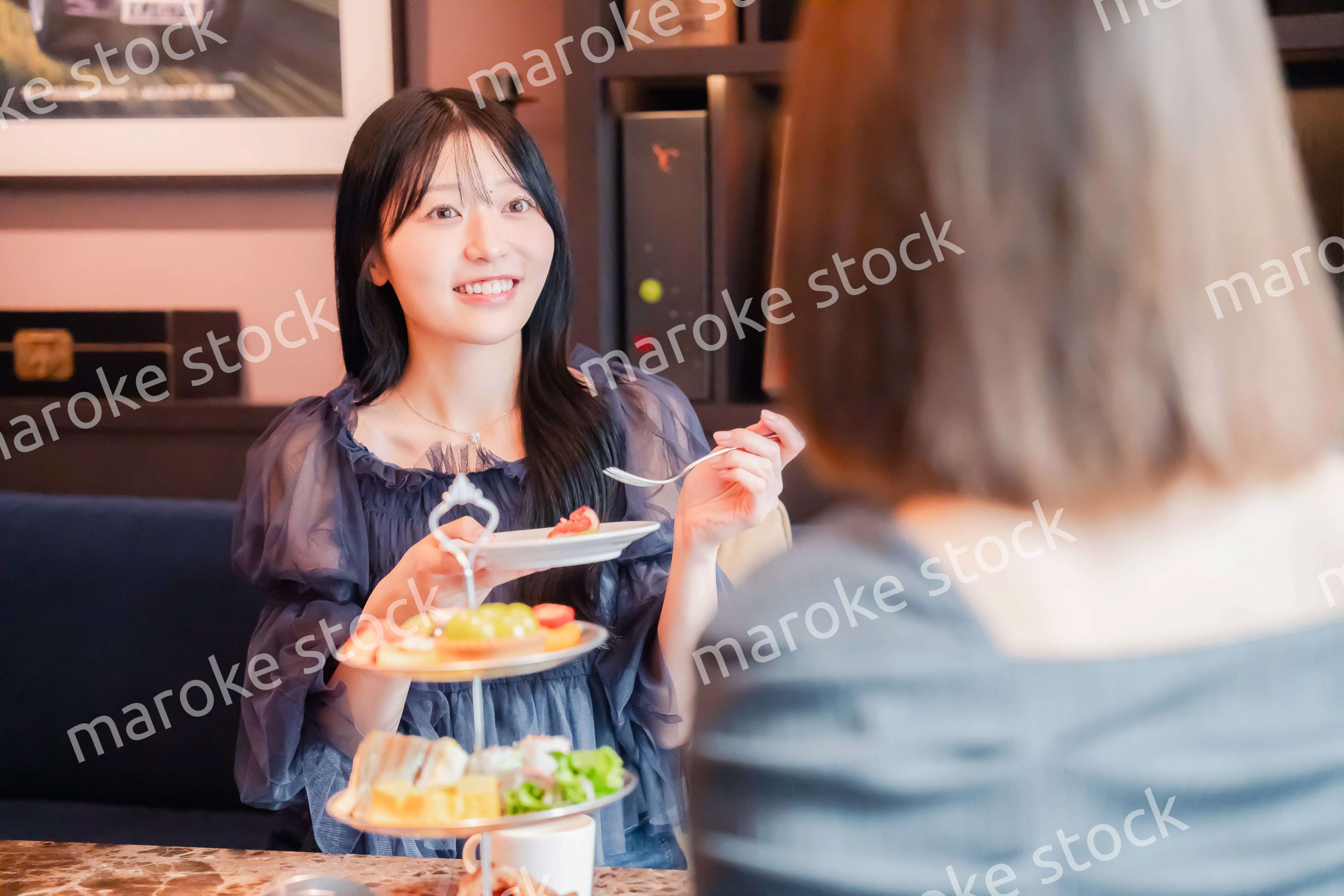 ホテルでアフタヌーンティーを楽しむ若い二人の女性