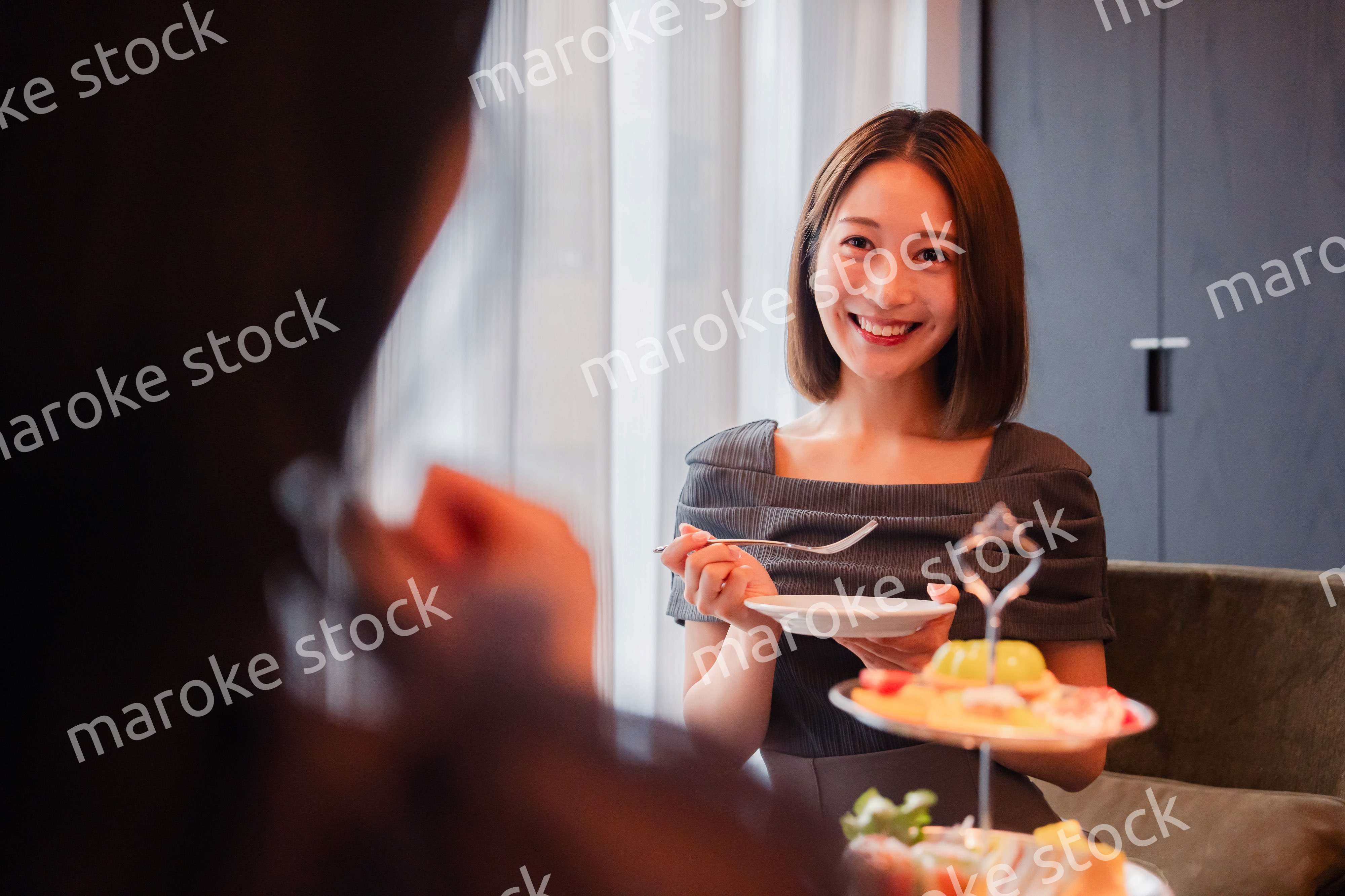 ホテルでアフタヌーンティーを楽しむ若い二人の女性