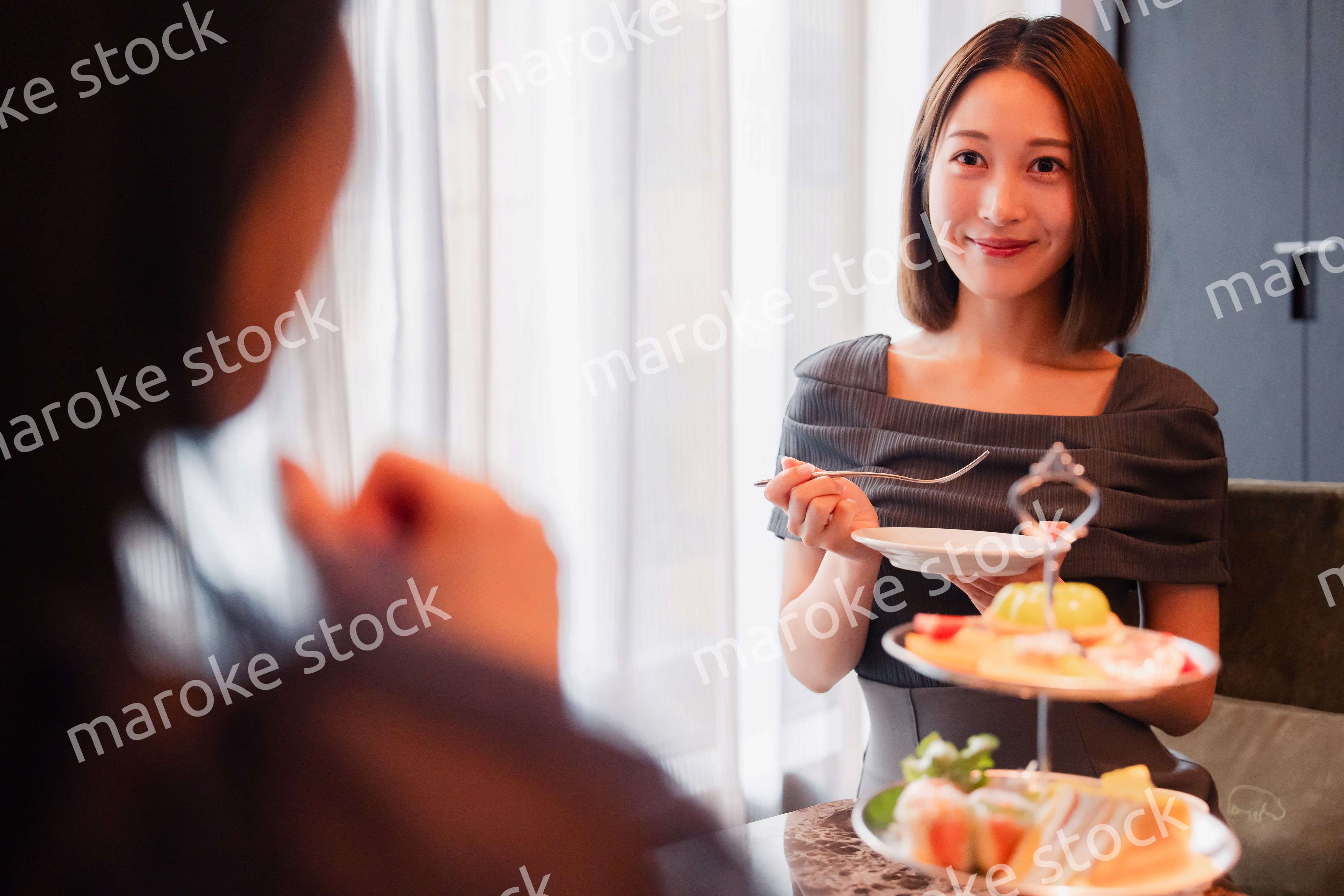 ホテルでアフタヌーンティーを楽しむ若い二人の女性