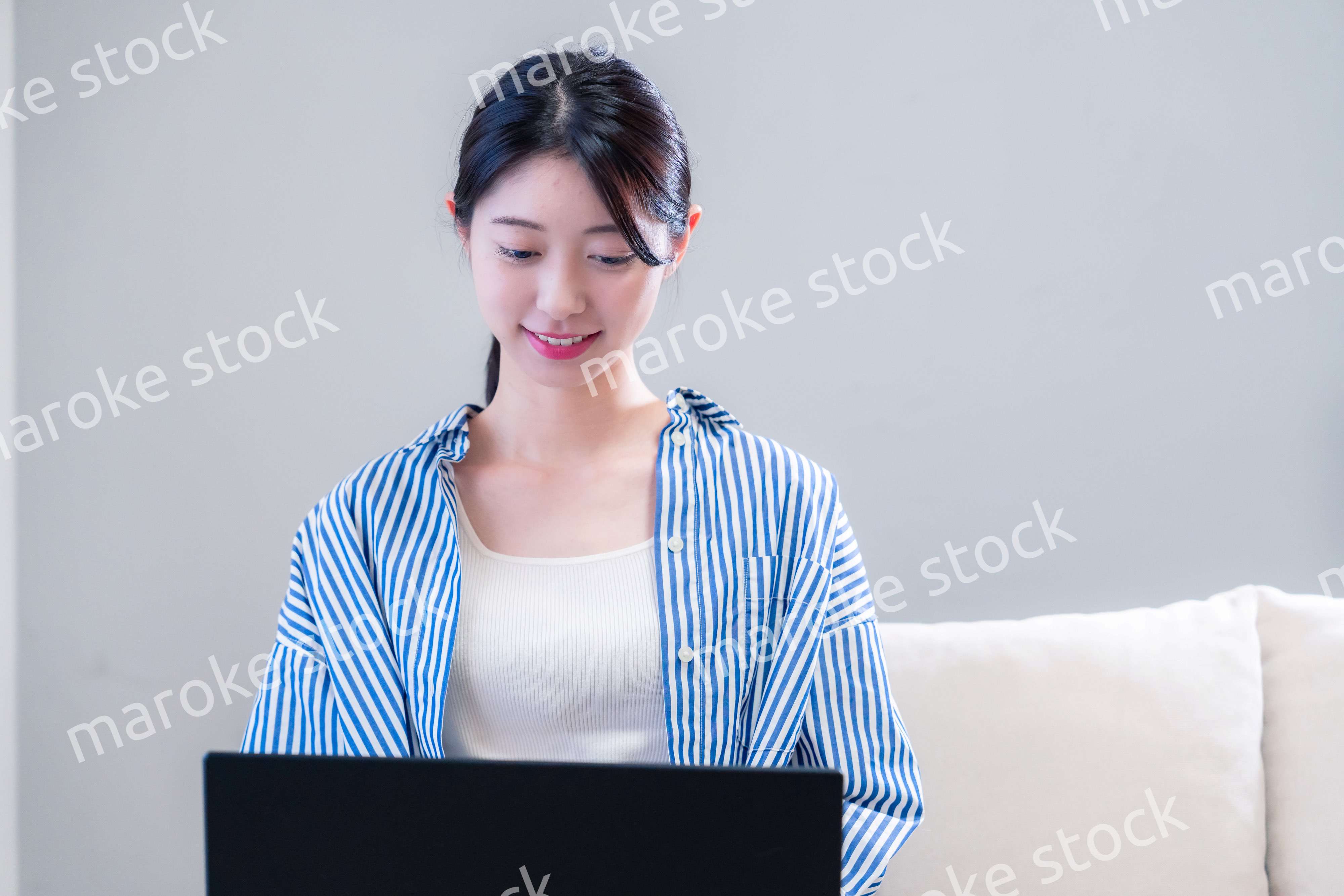 家で笑顔でパソコンを使う若い女性