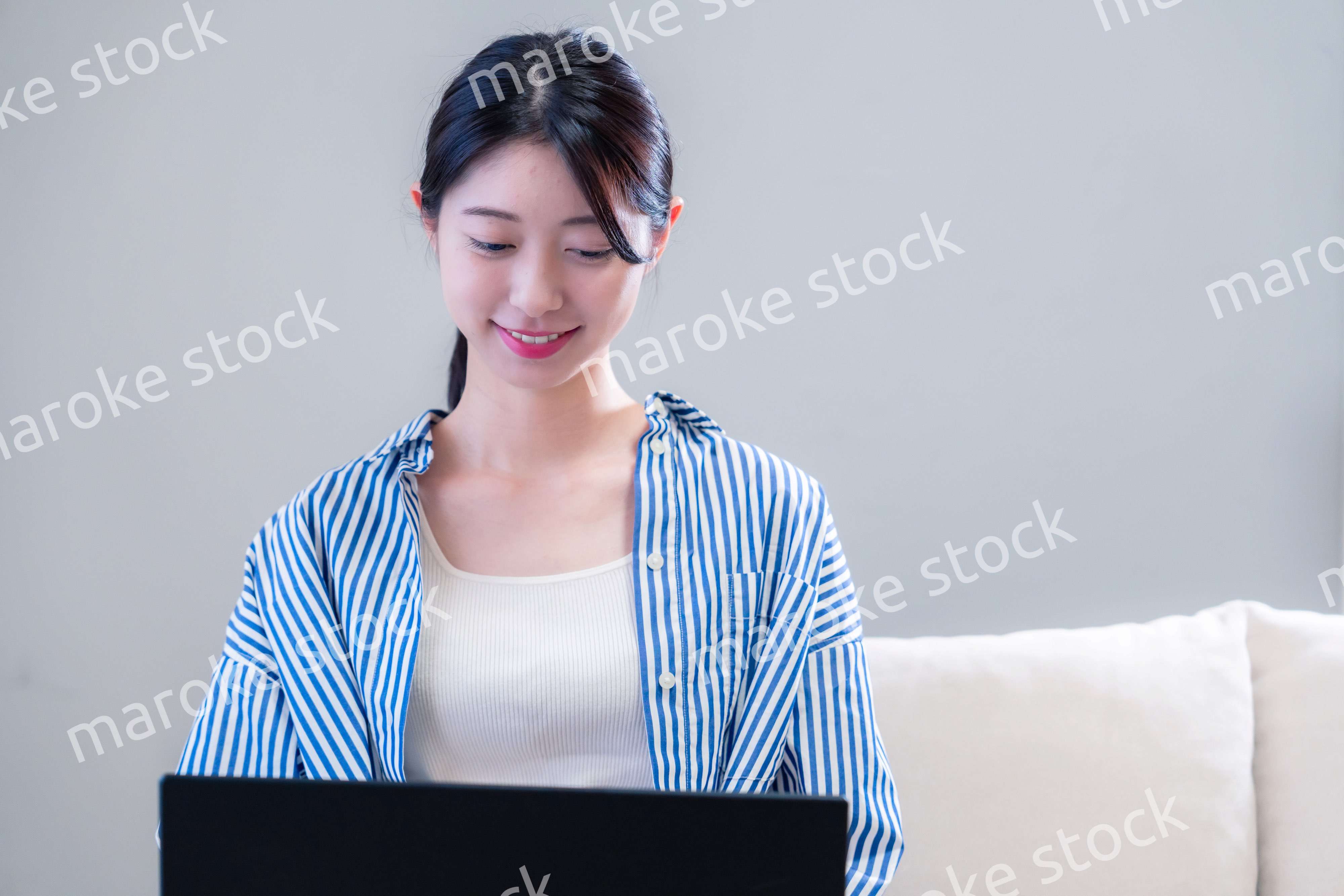 家で笑顔でパソコンを使う若い女性