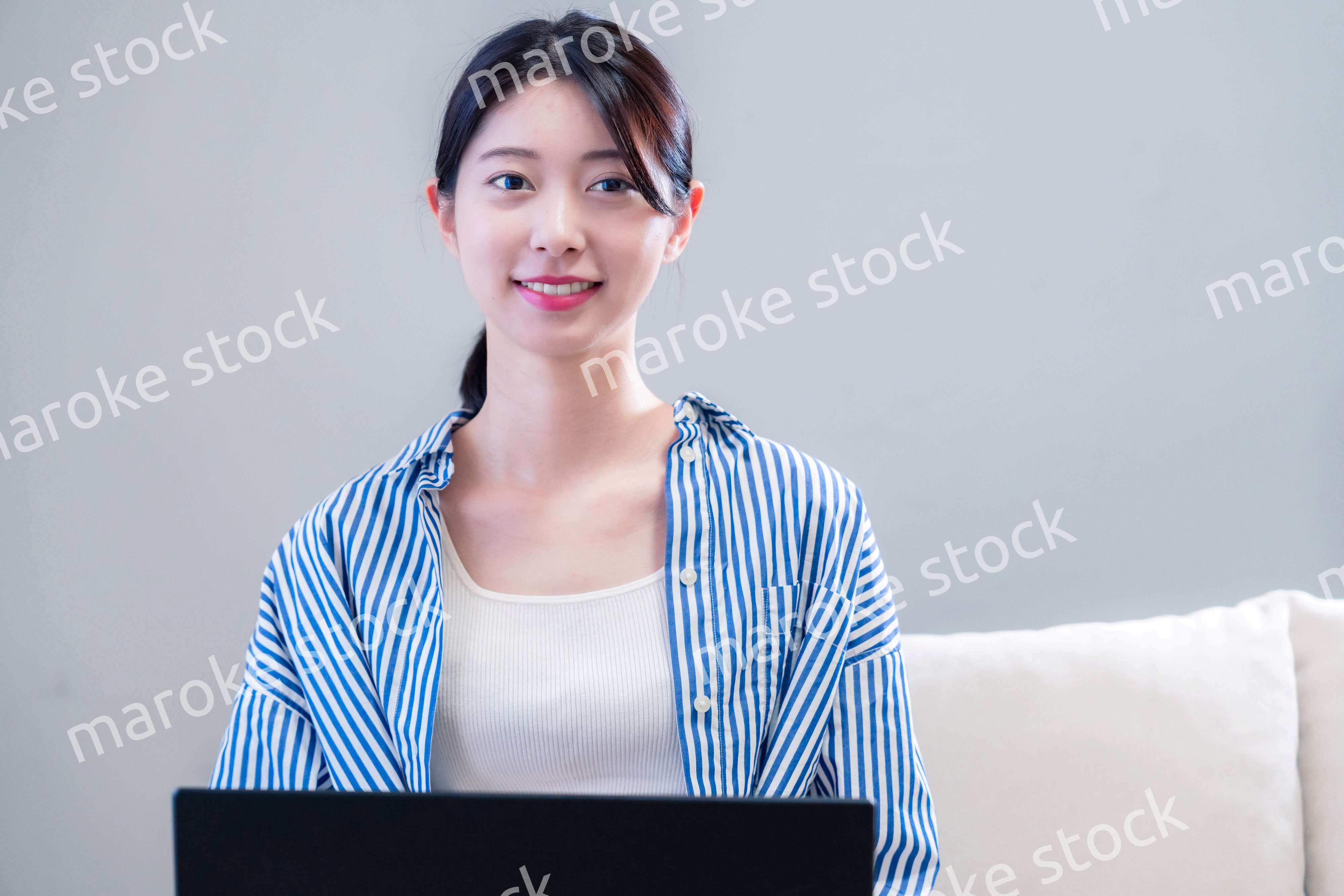 家で笑顔でパソコンを使う若い女性