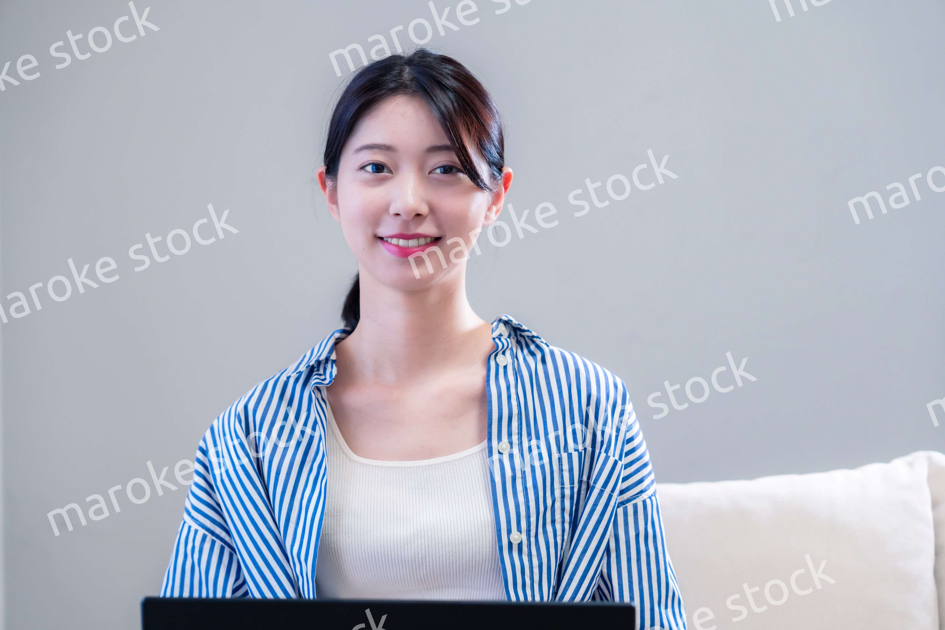 家で笑顔でパソコンを使う若い女性