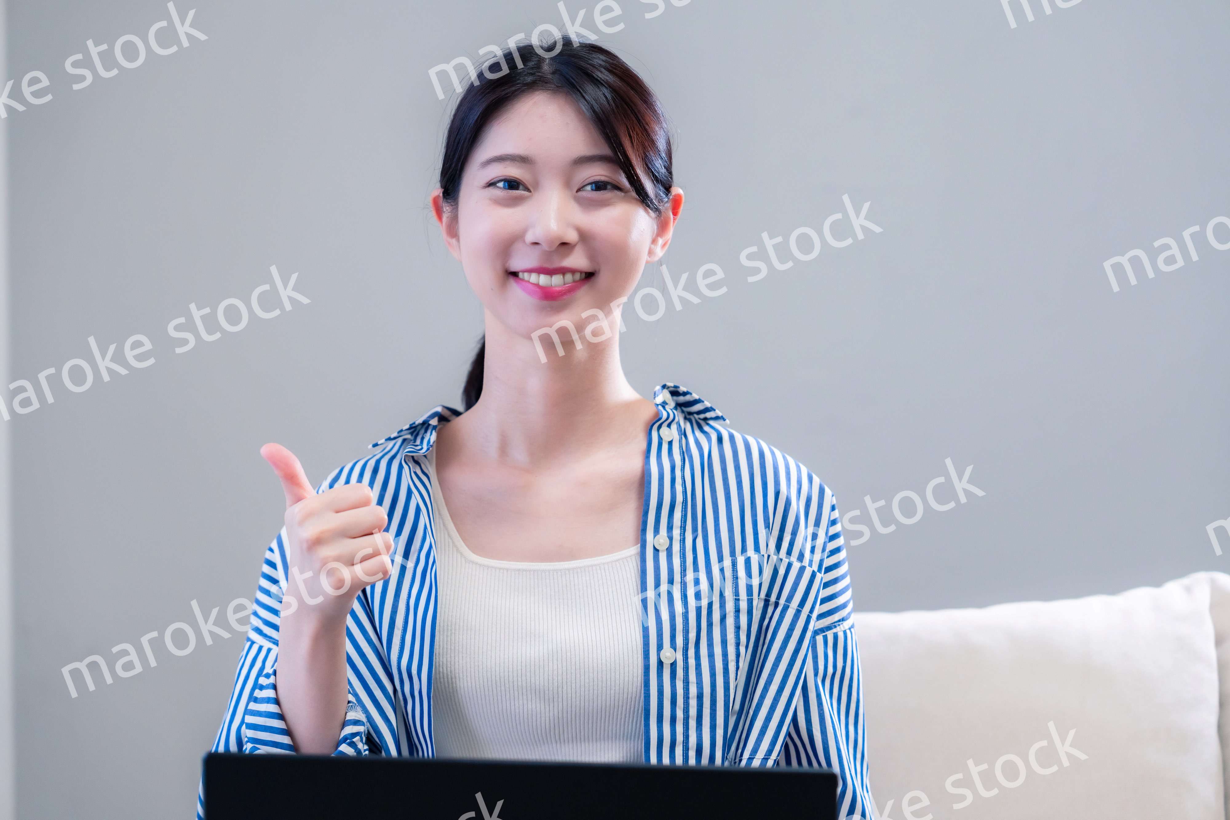 家で笑顔でパソコンを使う若い女性