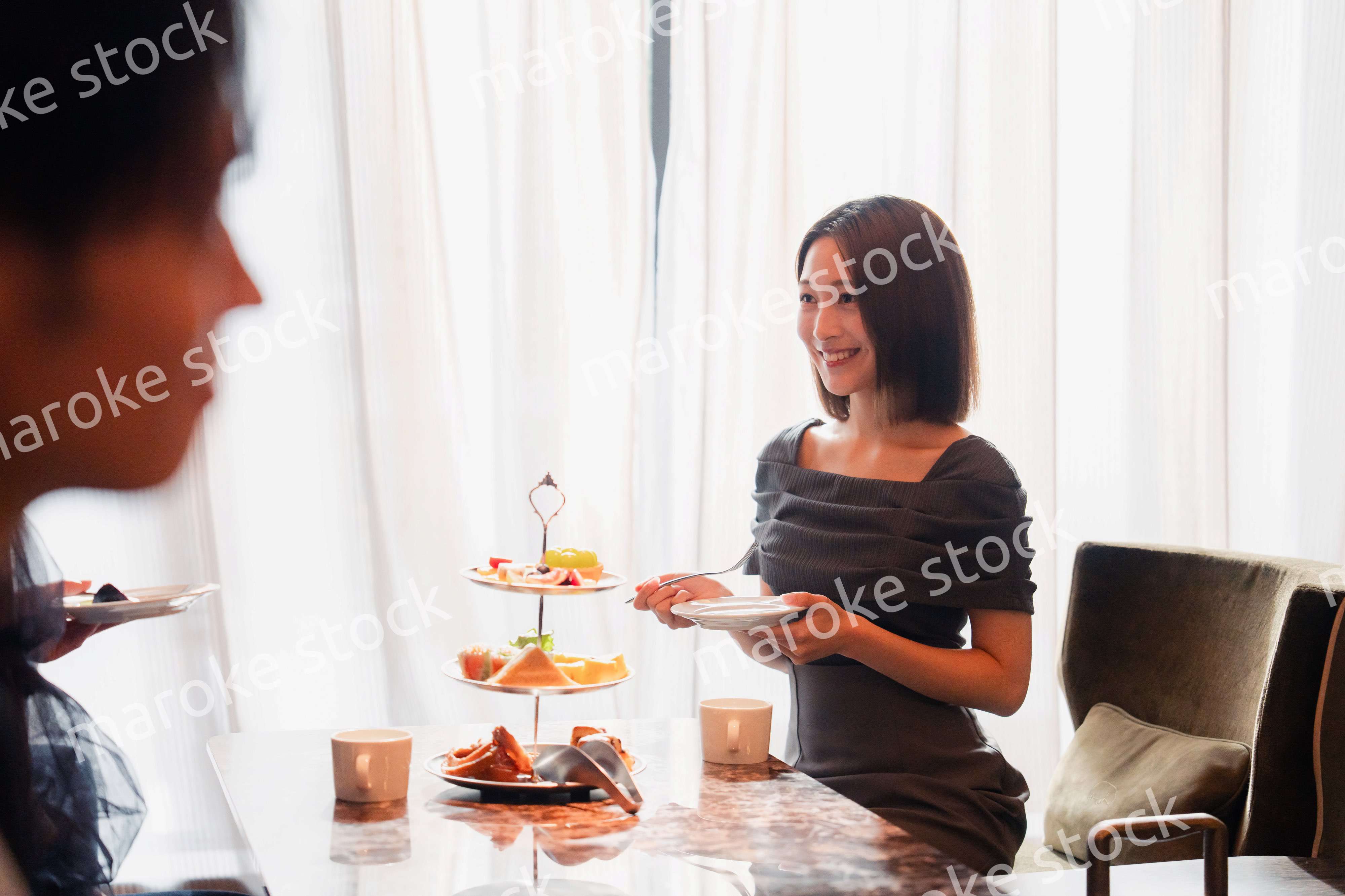 ホテルのアフタヌーンティーで女子会をする若い人々