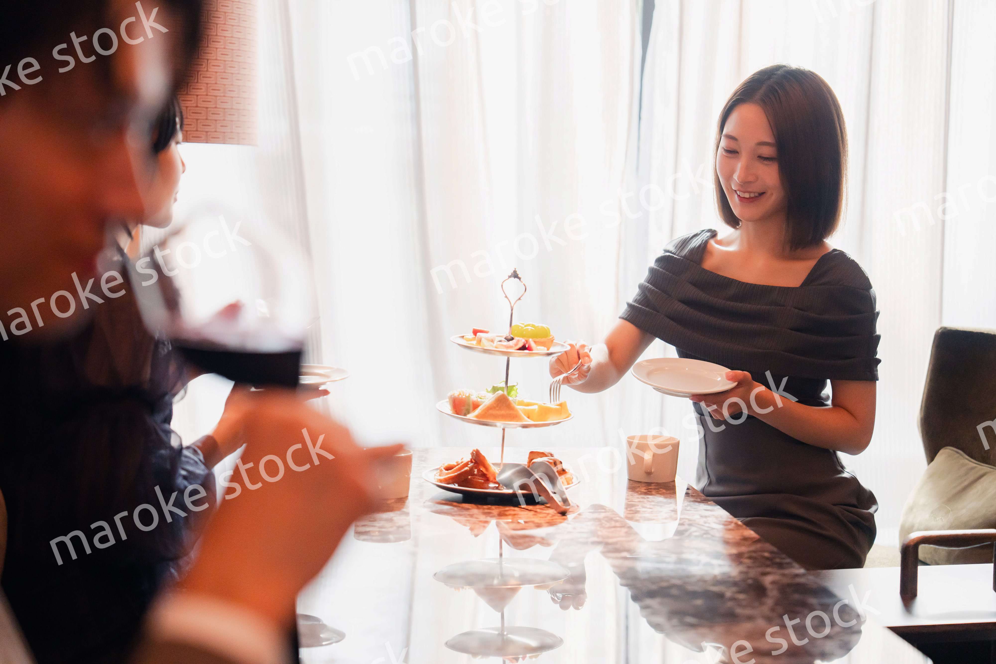 ホテルのアフタヌーンティーで女子会をする若い人々