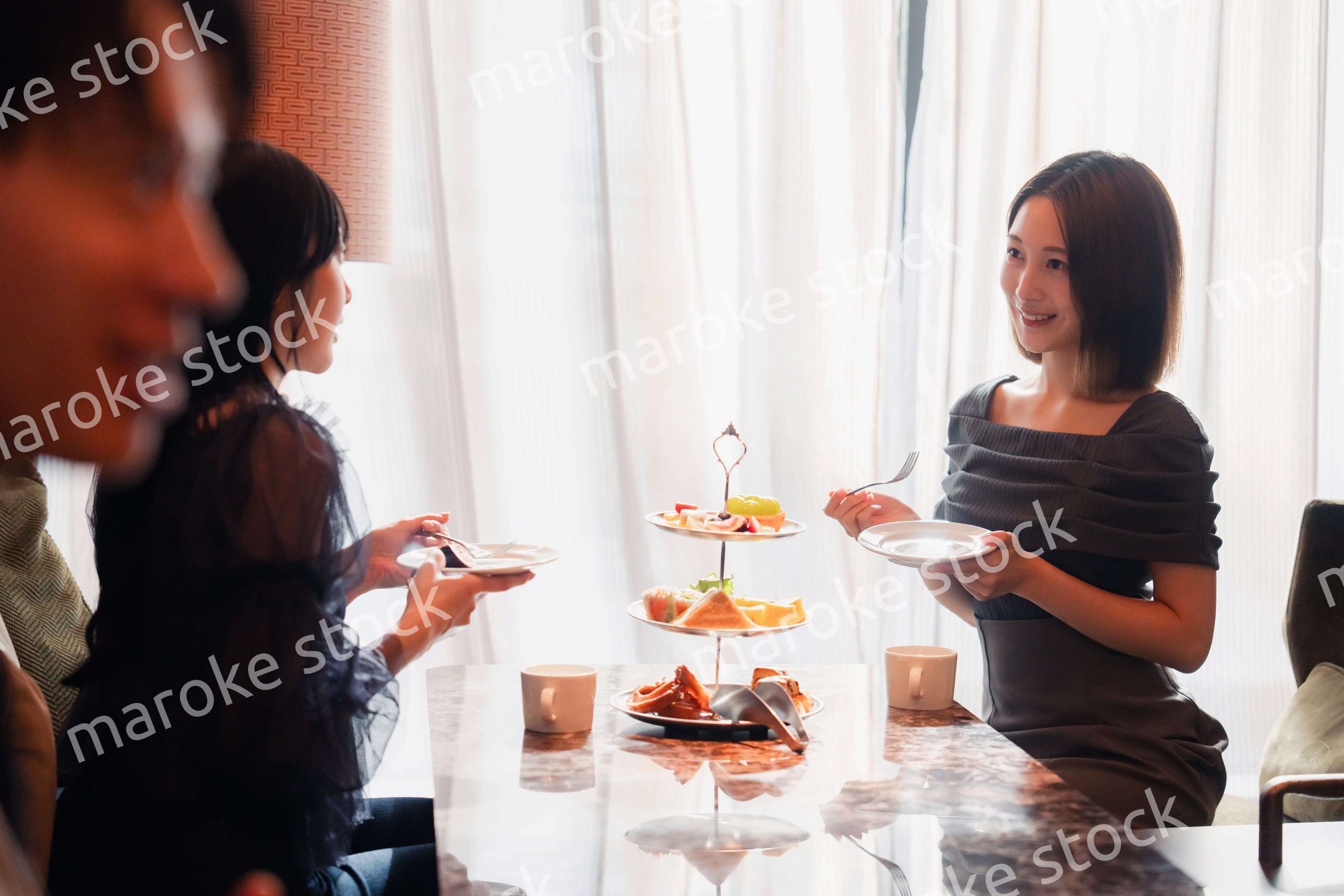 ホテルのアフタヌーンティーで女子会をする若い人々