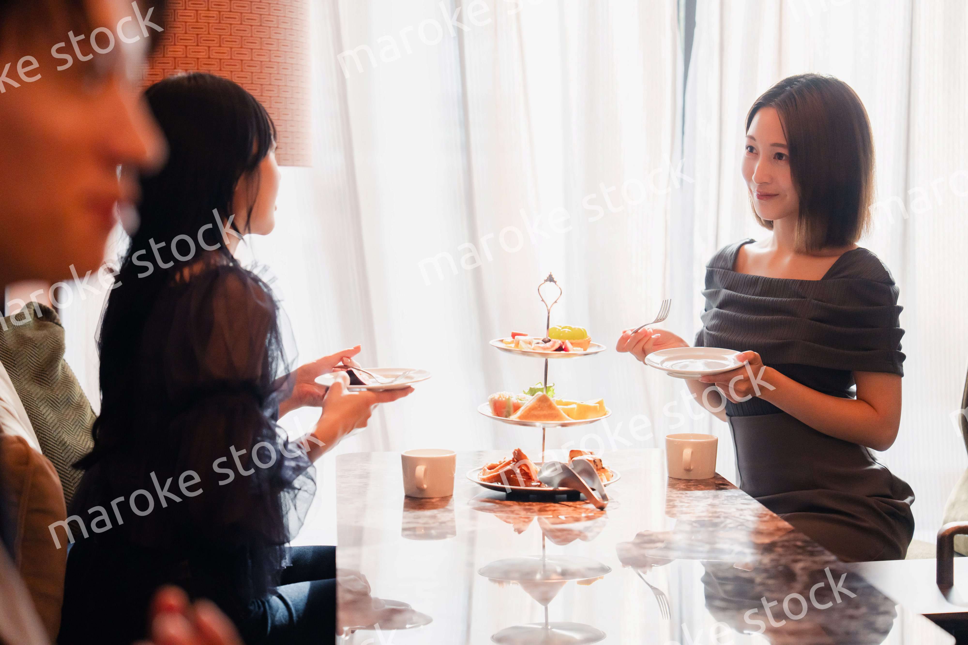 ホテルのアフタヌーンティーで女子会をする若い人々