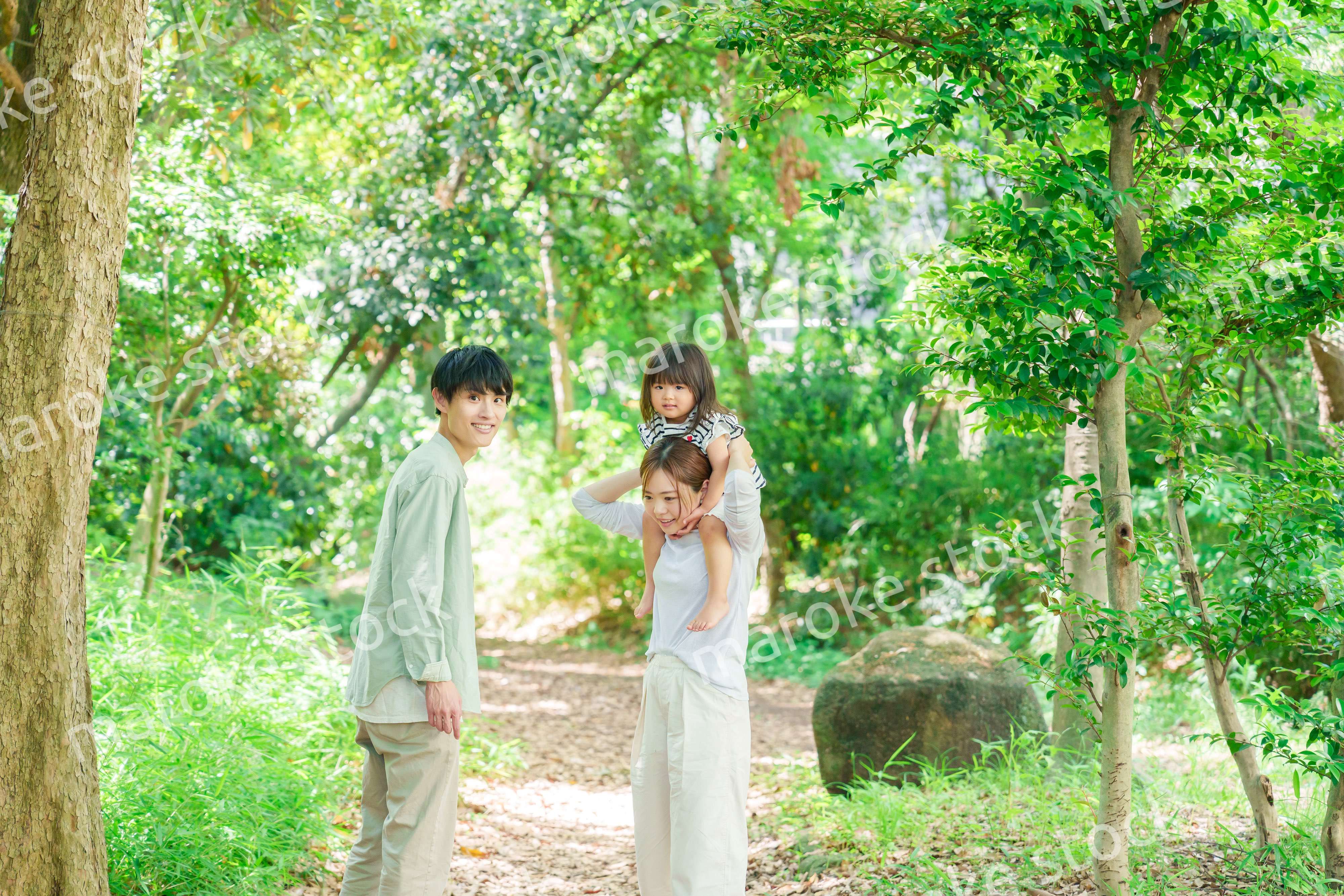 子どもを肩車して森の中を歩く家族