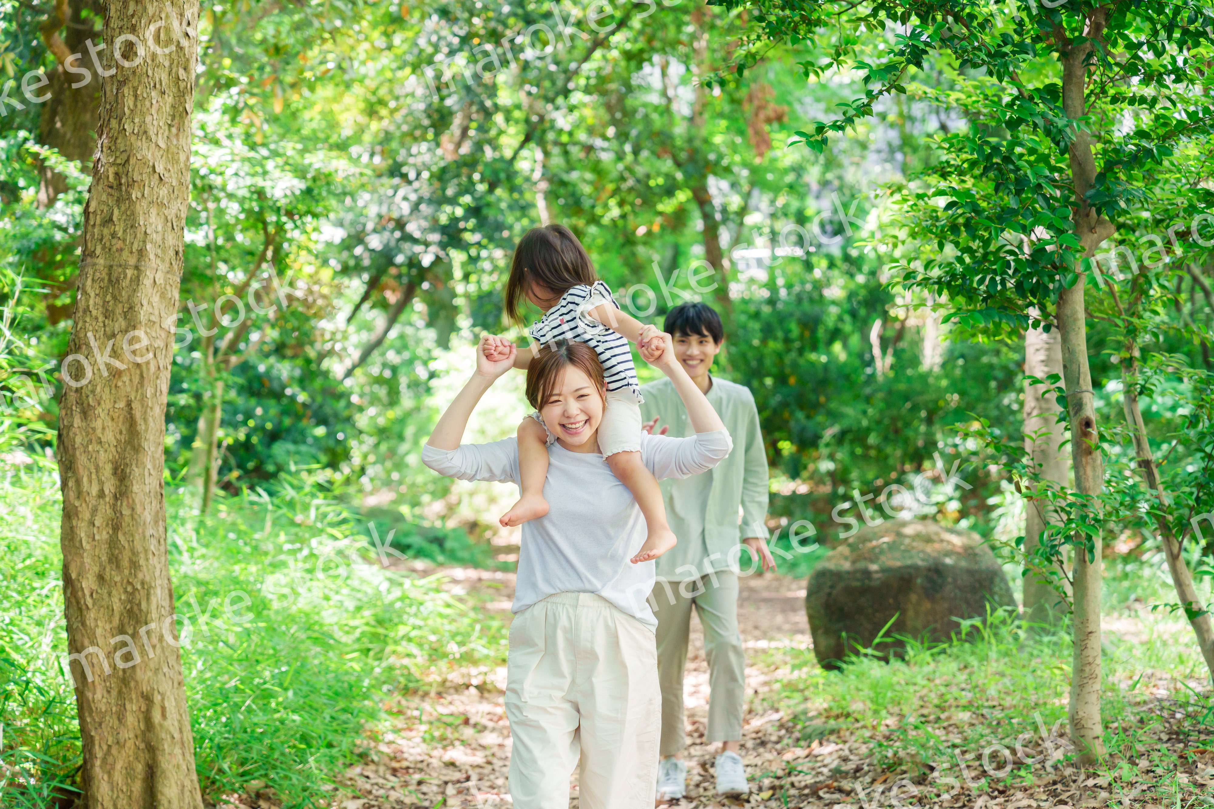 子どもを肩車して森の中を歩く家族