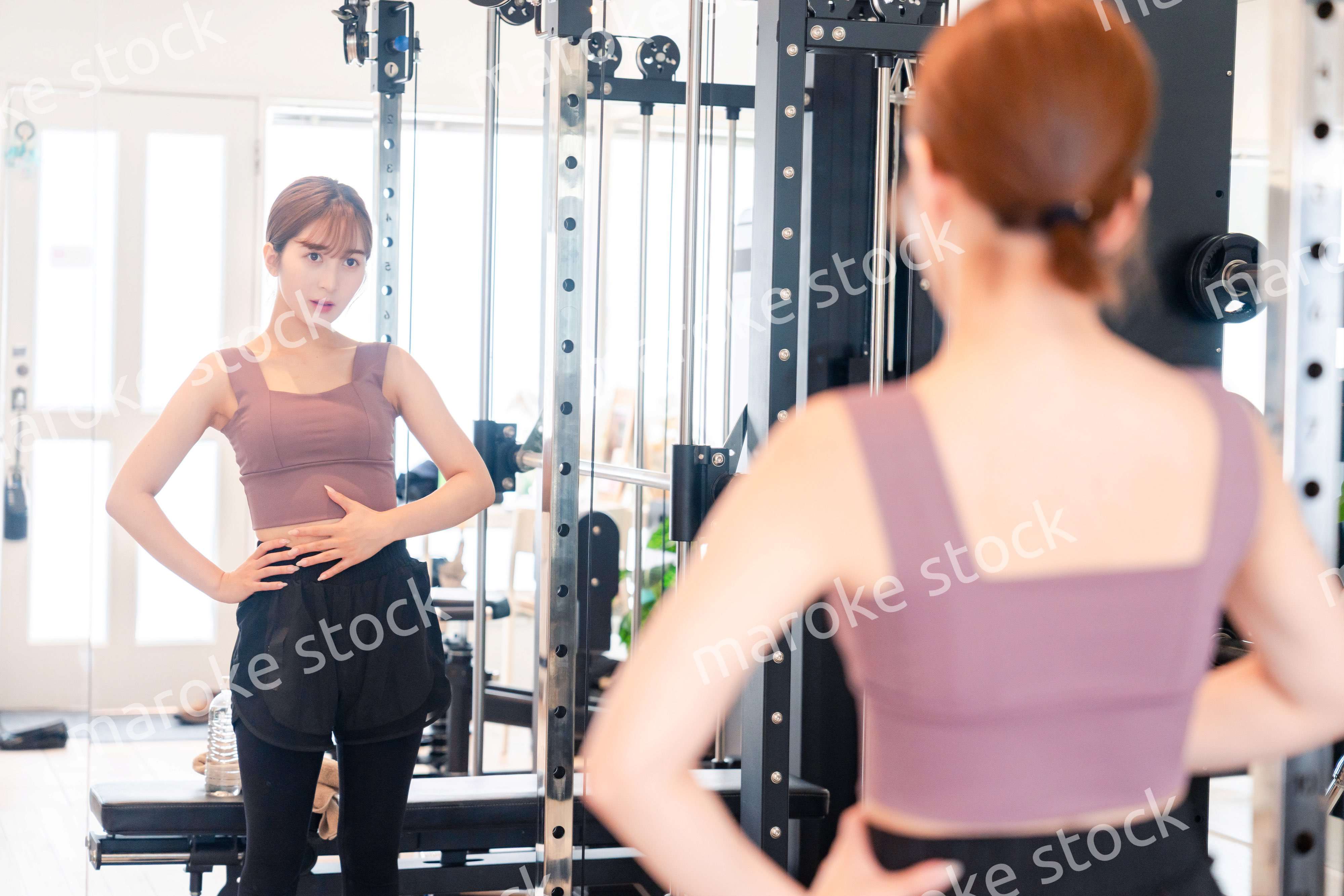 ジムで自分の体型を確認する若い女性