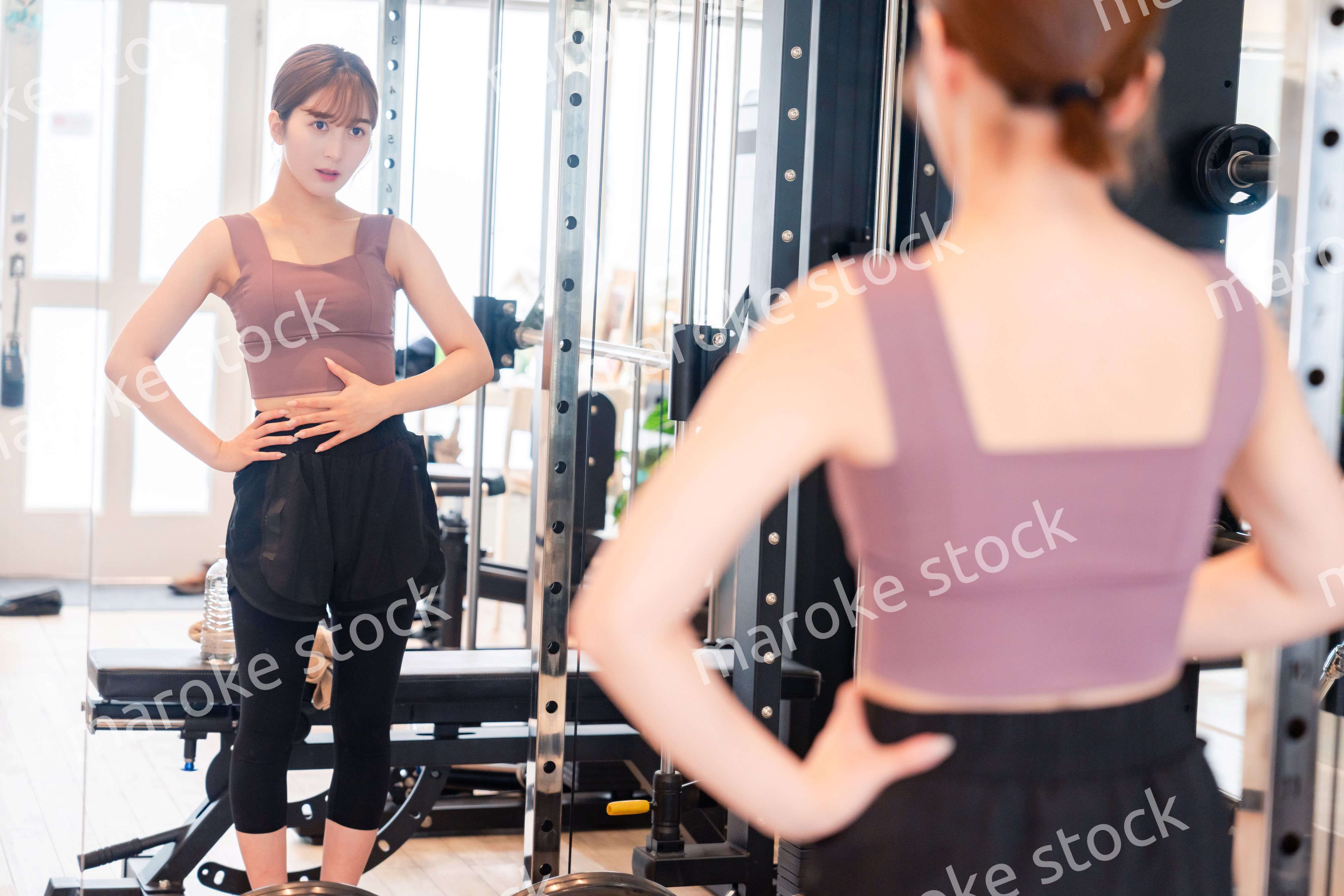 ジムで自分の体型を確認する若い女性