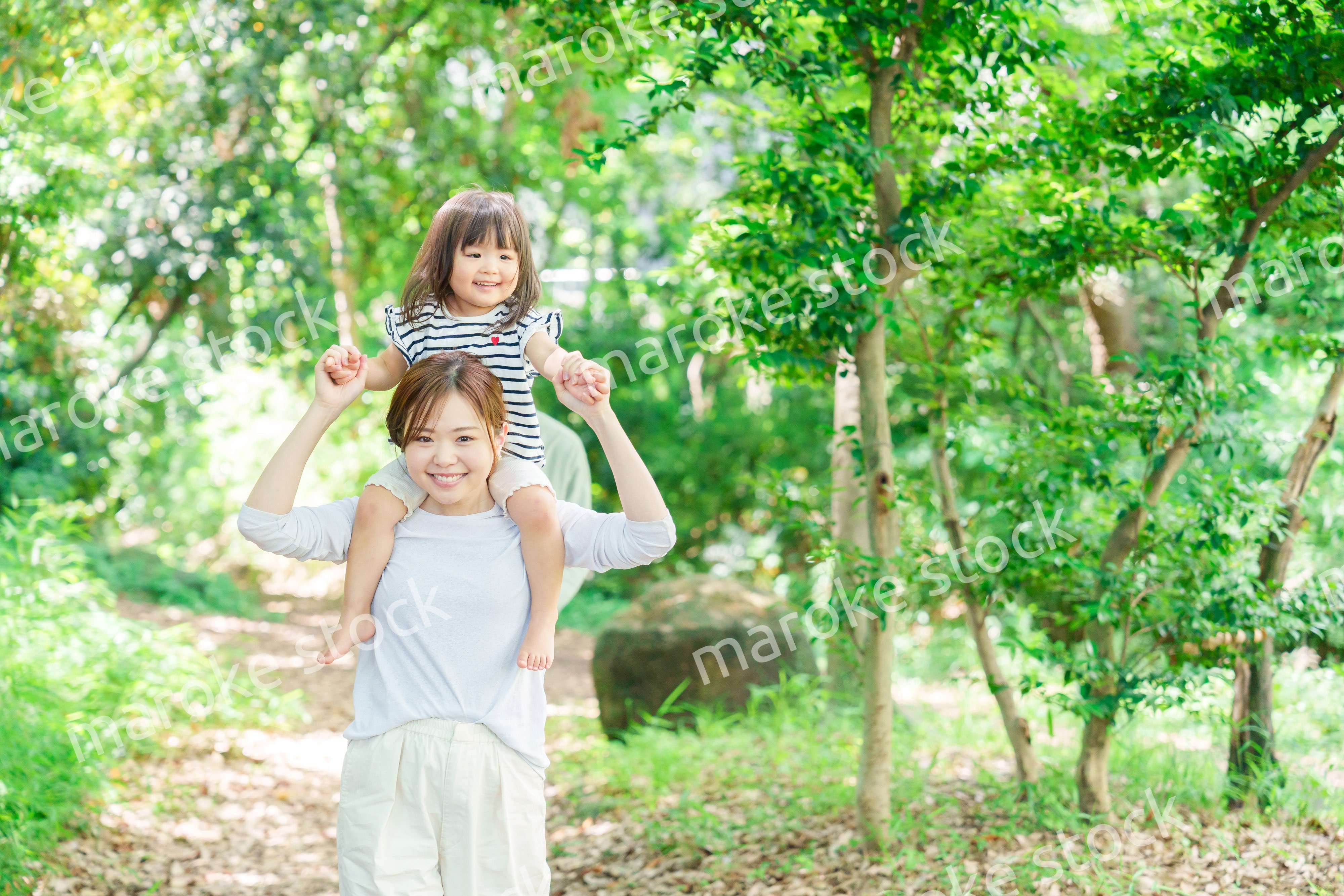 子どもを肩車して森の中を歩く家族