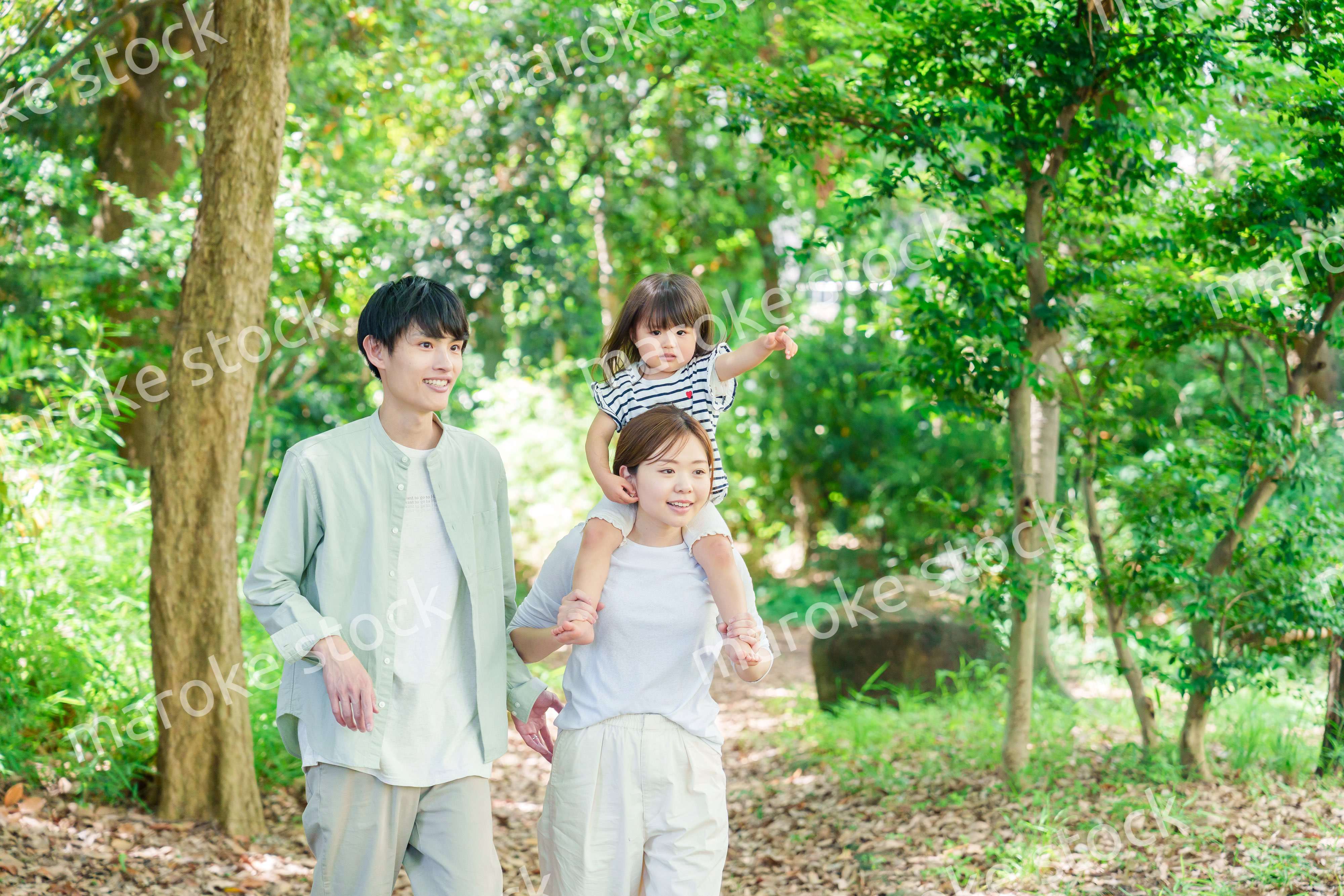 子どもを肩車して森の中を歩く家族