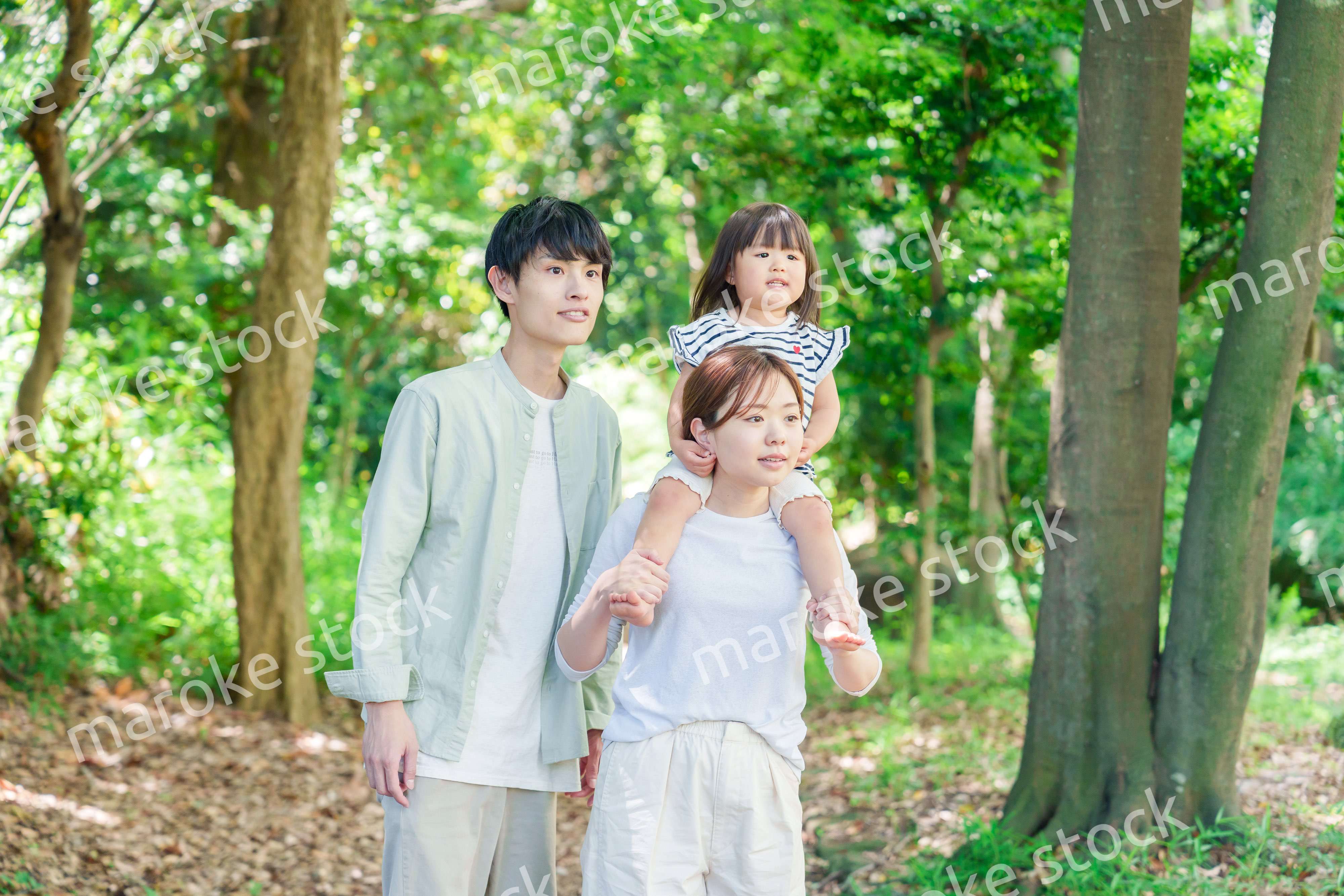 子どもを肩車して森の中を歩く家族