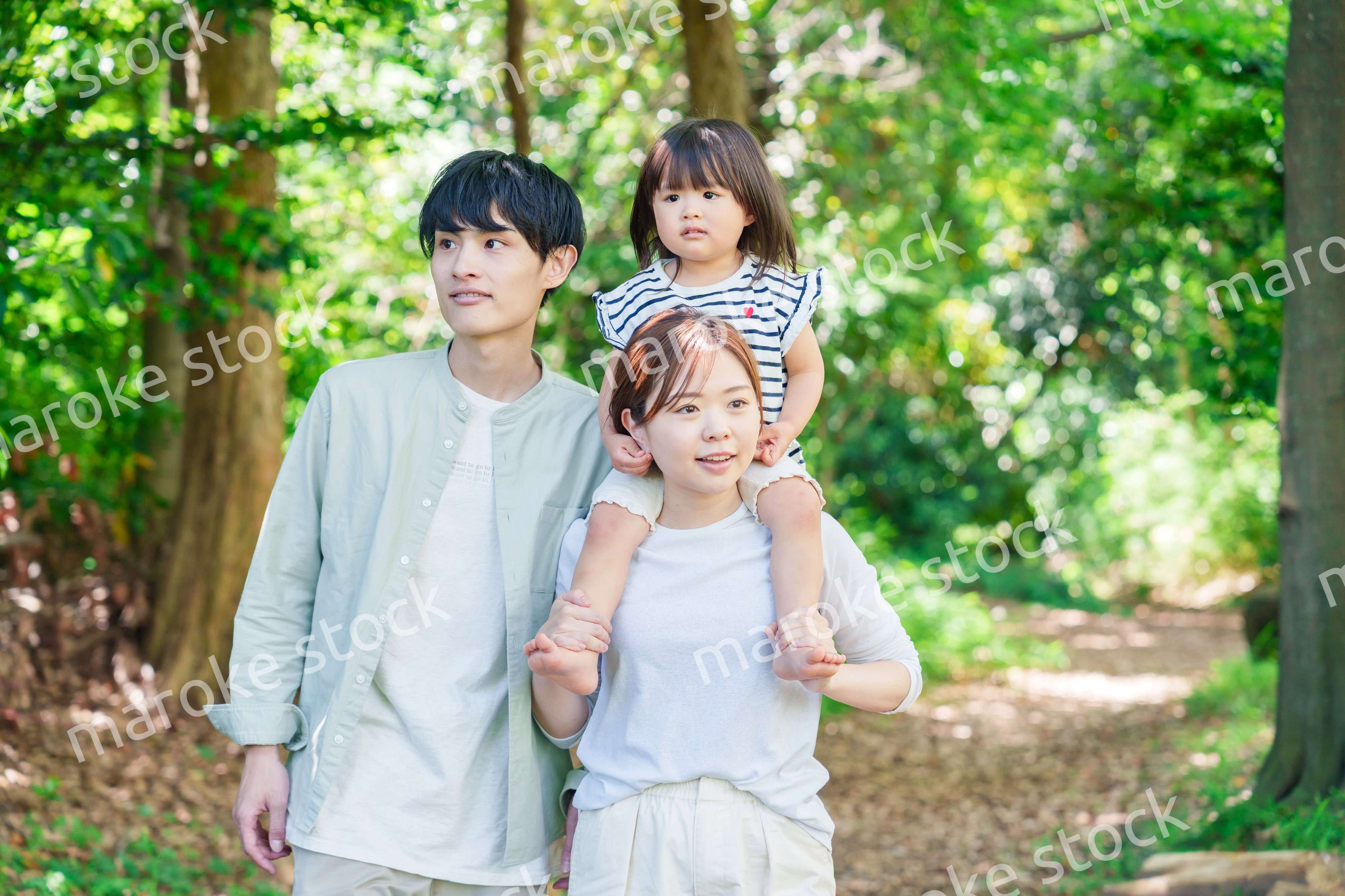 子どもを肩車して森の中を歩く家族