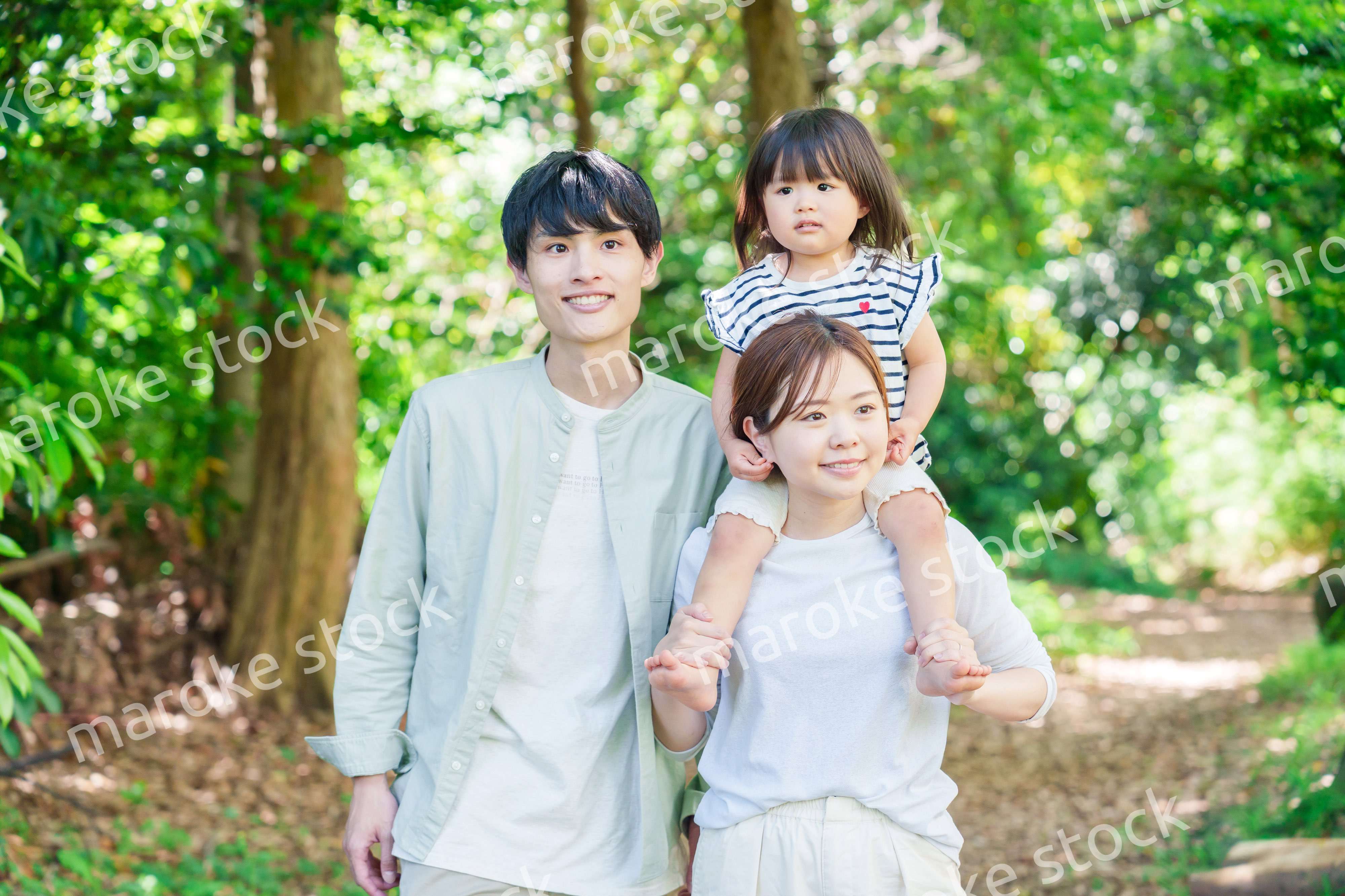 子どもを肩車して森の中を歩く家族