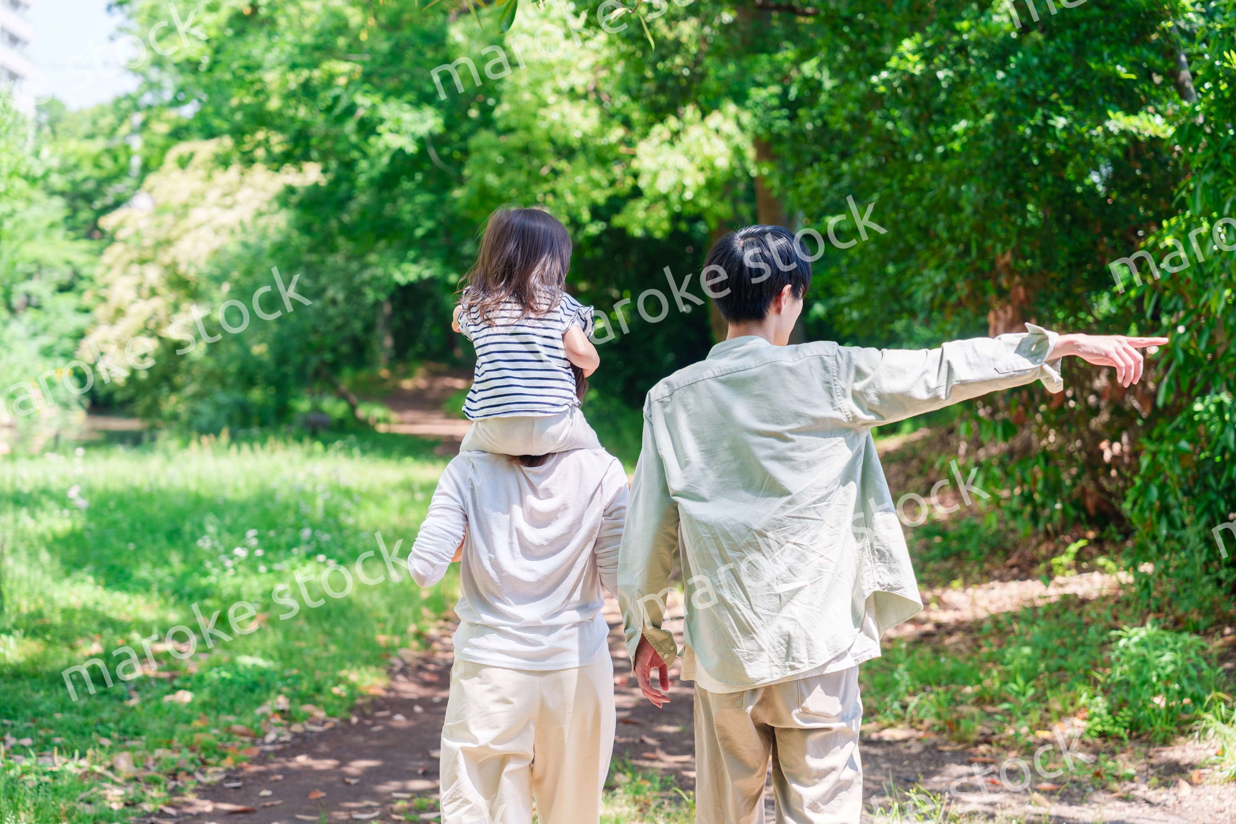 子どもを肩車して森の中を歩く家族